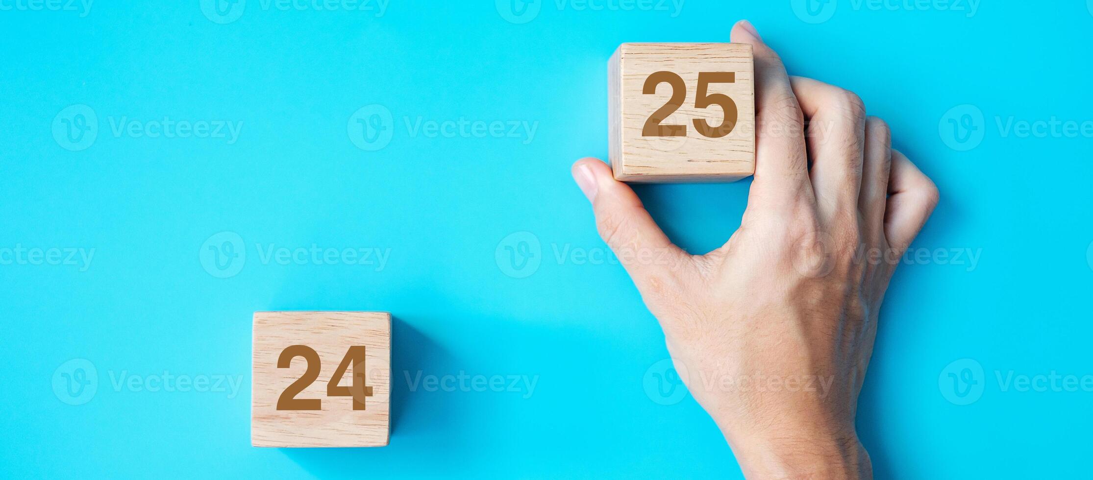 hand holding wooden cube block with 2025 text on blue background. Resolution, plan, review, goal, start and New Year holiday concepts photo