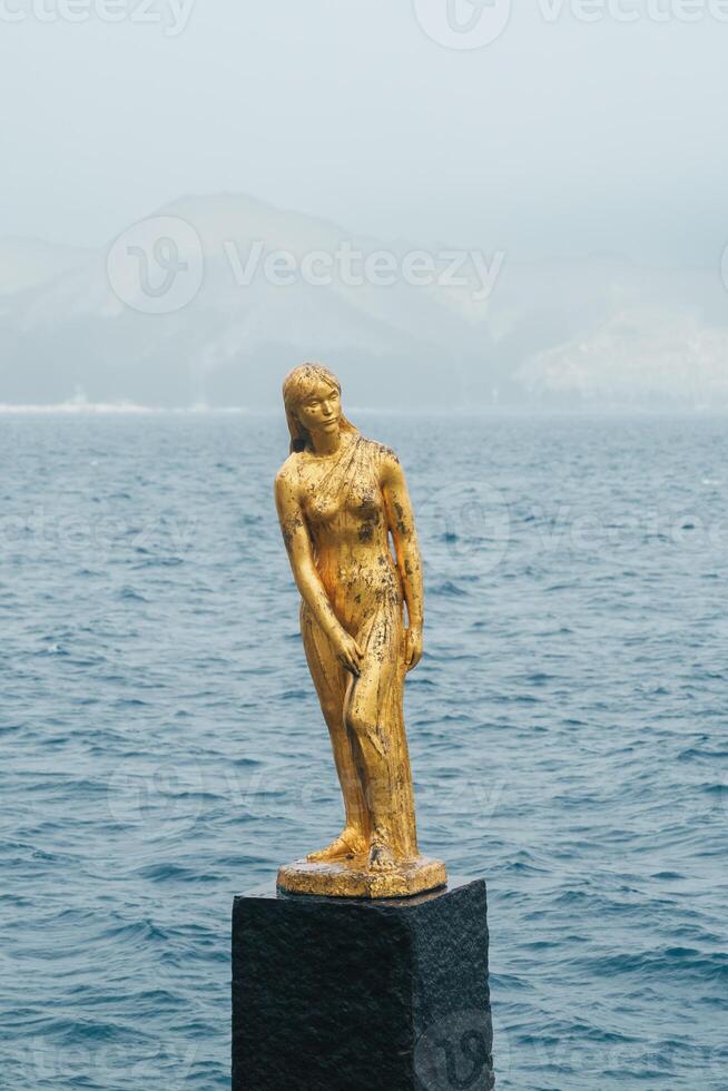 The iconic golden statue of the legendary local girl Tatsuko and lake Tazawa in winter. located in Semboku city, Akita Prefecture, northern Japan. Landmark for tourist attraction in Tohoku region photo