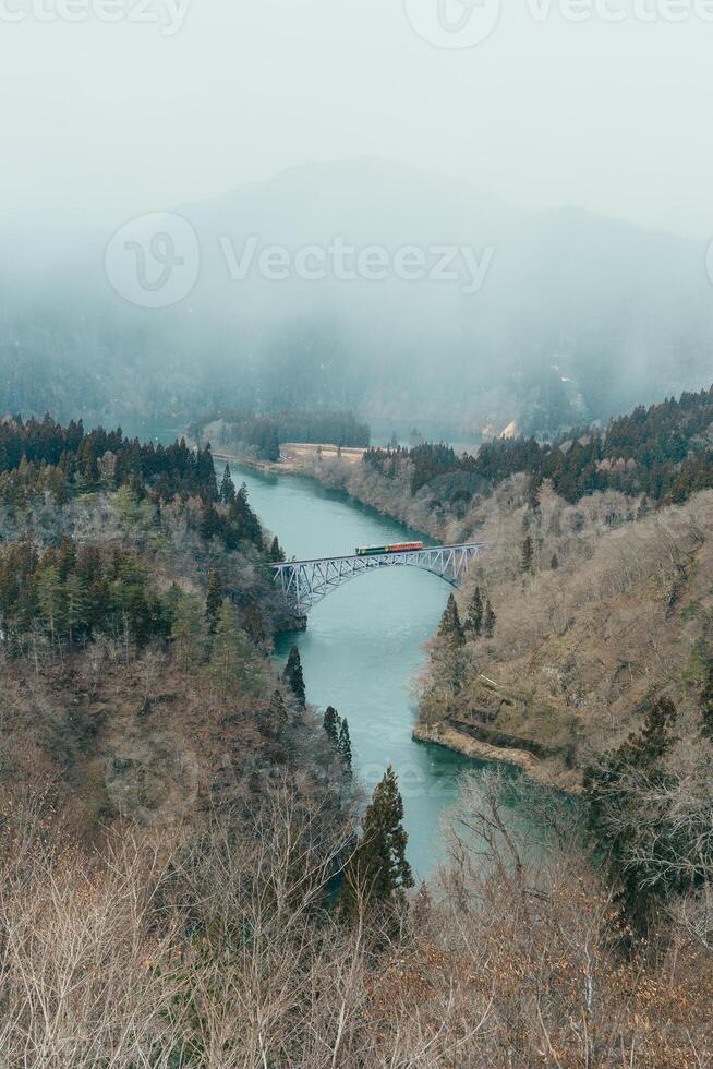 Panoramic View of Japan local train with Tadami river and bridge. Tadami Railway Line in The Valley at Mishima Machi, Aizu, Fukushima Prefecture, Japan. Landmark and iconic spot for tourist attraction photo