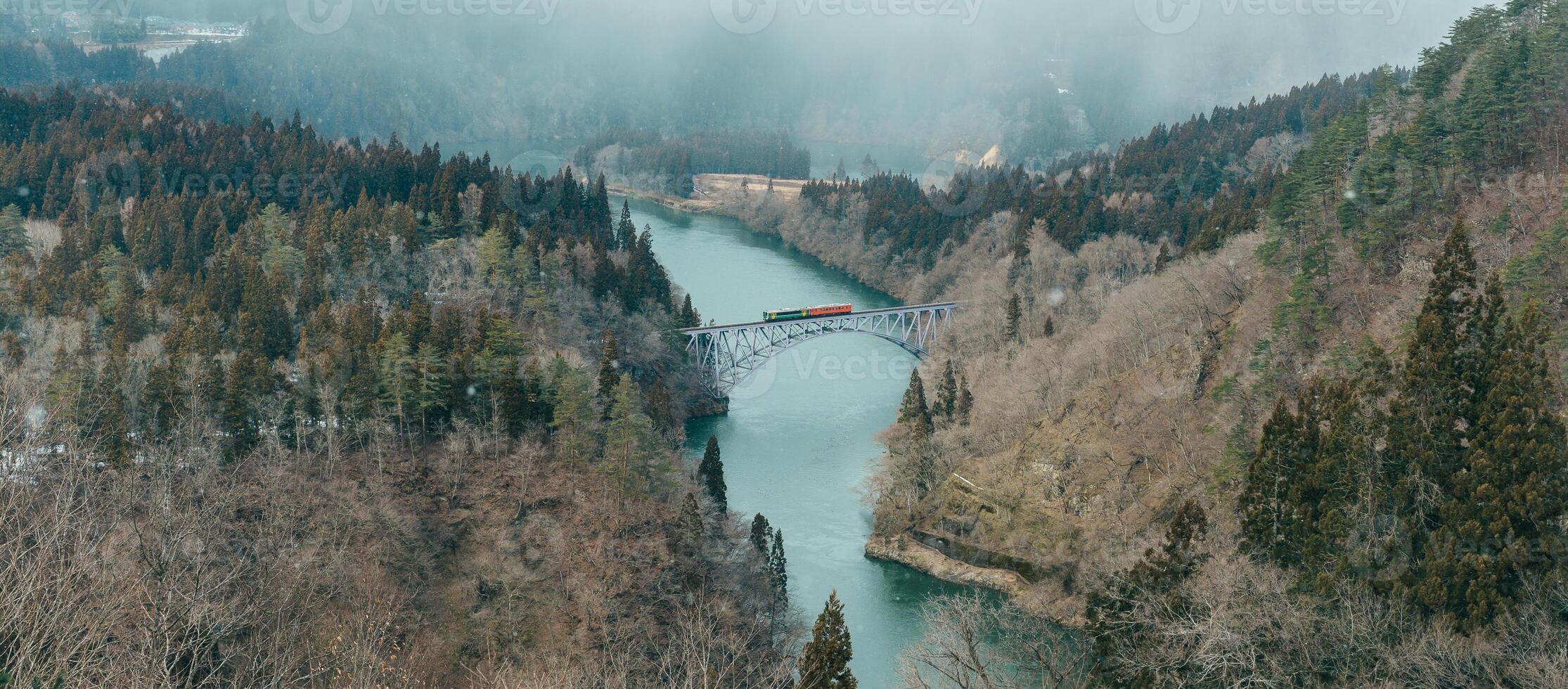 Panoramic View of Japan local train with Tadami river and bridge. Tadami Railway Line in The Valley at Mishima Machi, Aizu, Fukushima Prefecture, Japan. Landmark and iconic spot for tourist attraction photo