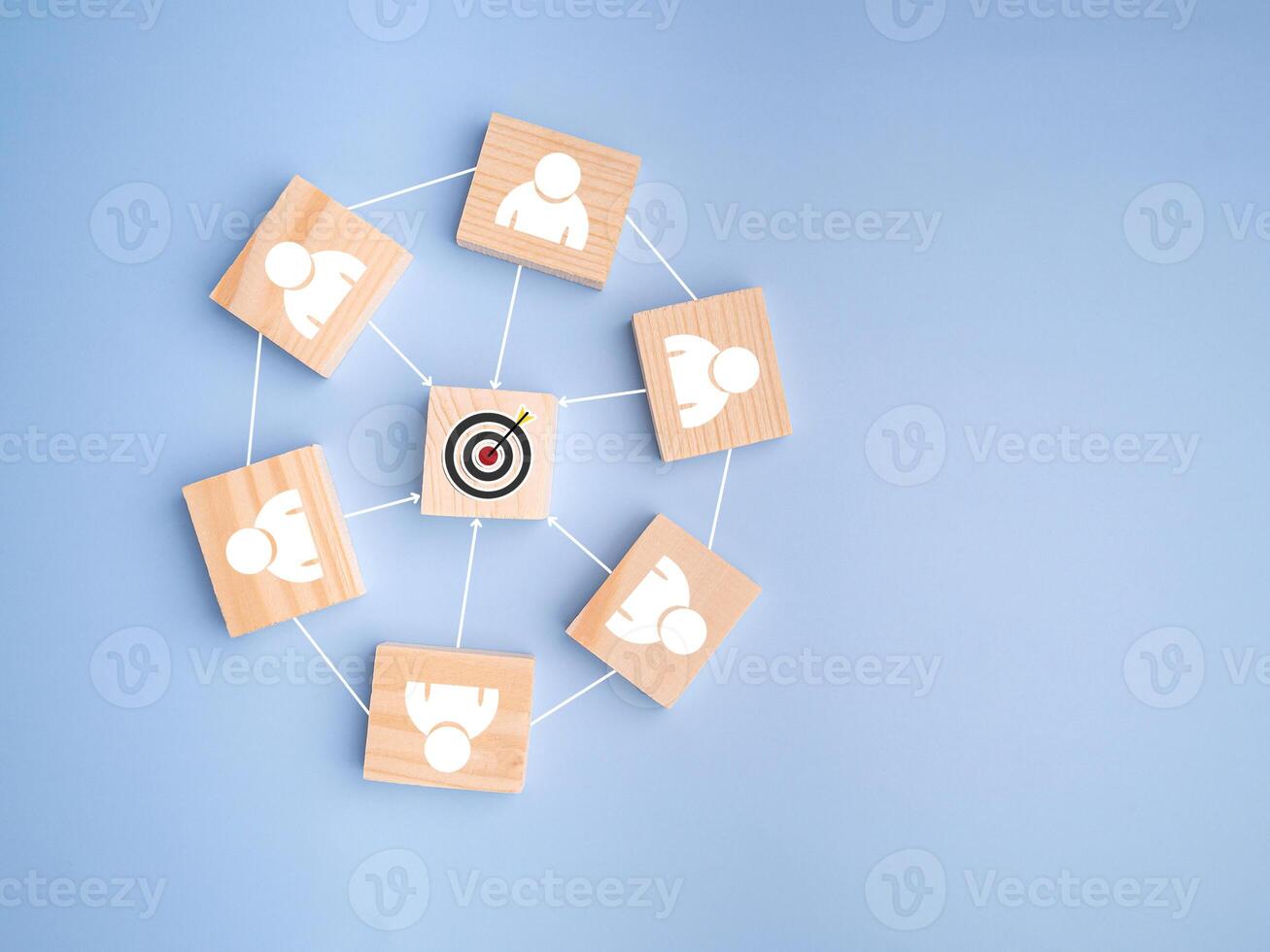 Top view of wooden blocks with white human icons and goal icon laid scattered on a light blue background, photo