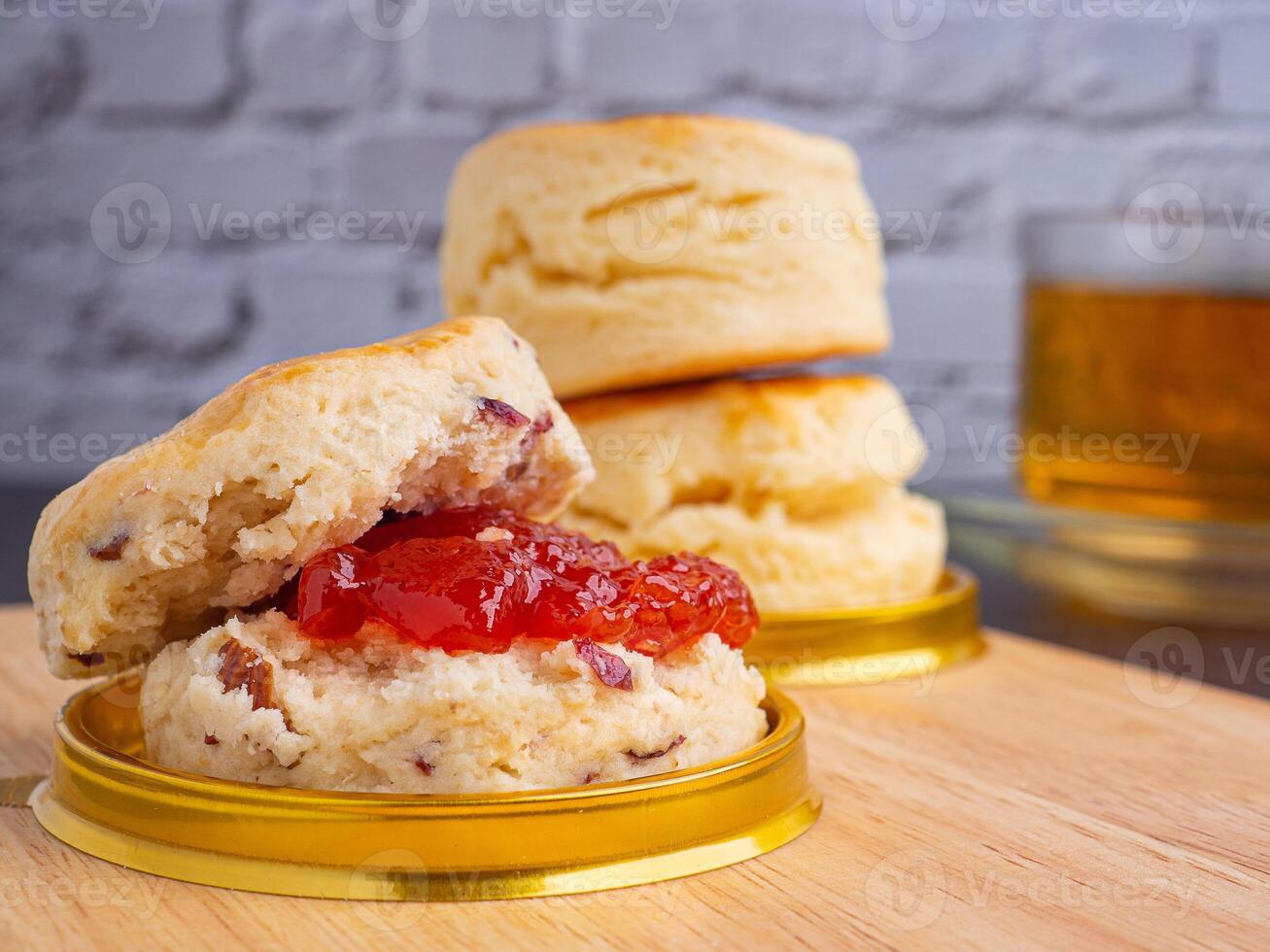 Traditional English style scones delicious freshly baked homemade with strawberry jam on a plate placed on wooden cutting board and teacup. Top view with copy space for text photo