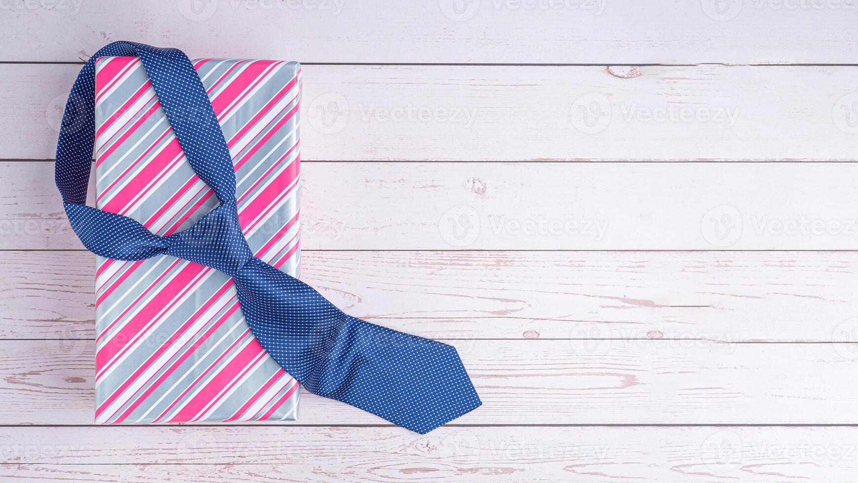 Happy Father's Day with a blue tie and a gift box on wooden background with space for text. Top view. Flat lay photo