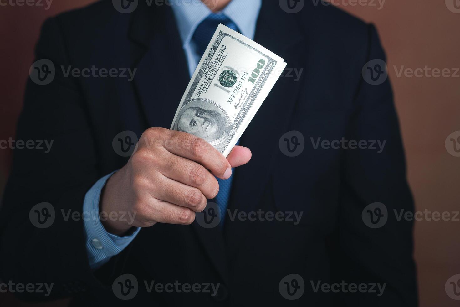 Hand of a businessman holding US dollars while standing with a brown background. Personal loans or business loans. Space for text. Close-up photo. Business and finance concept photo
