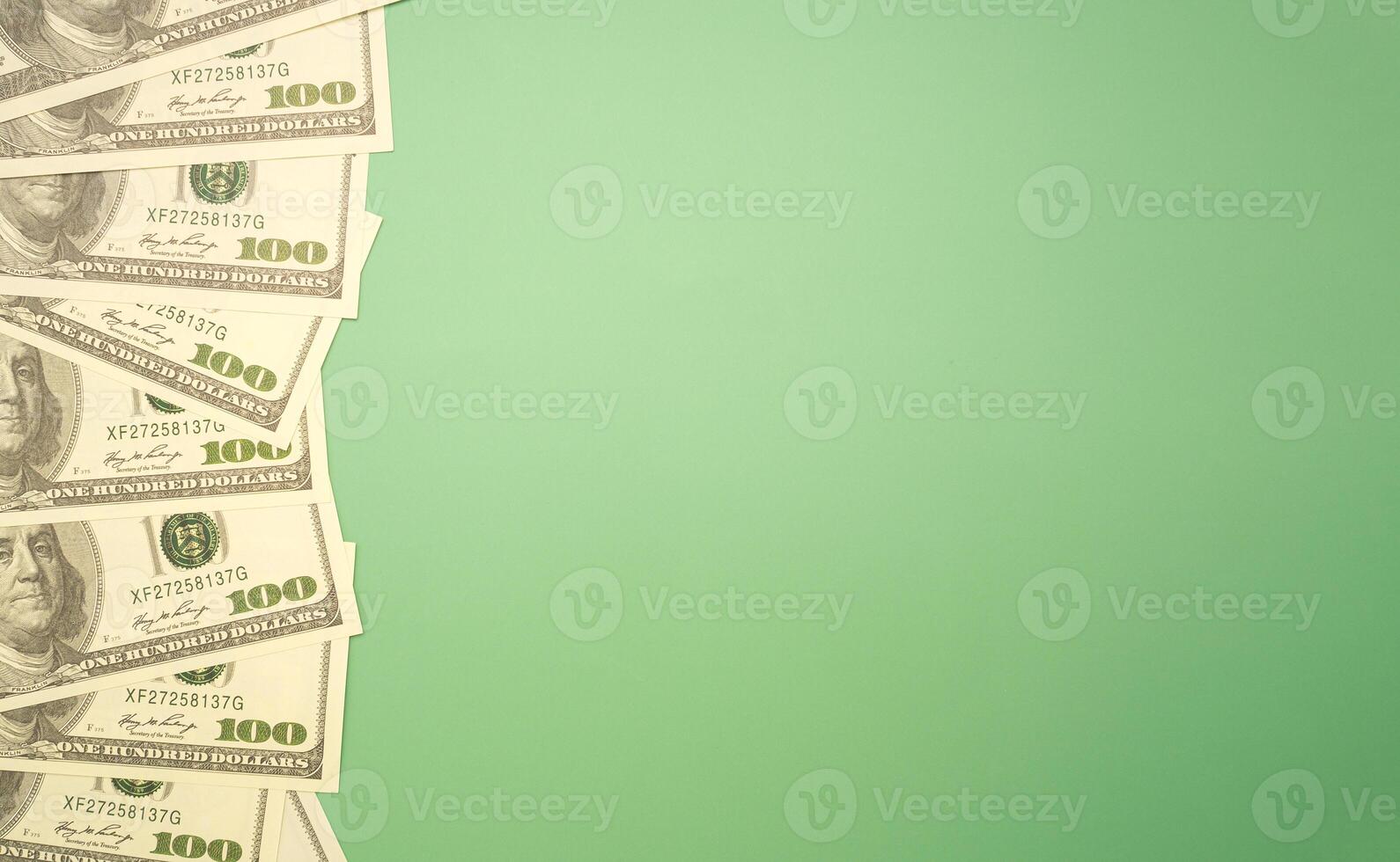 Top view of one hundred dollar banknotes laid isolated green background. Flat lay. Space for text. USD currency, business, and finance concept photo