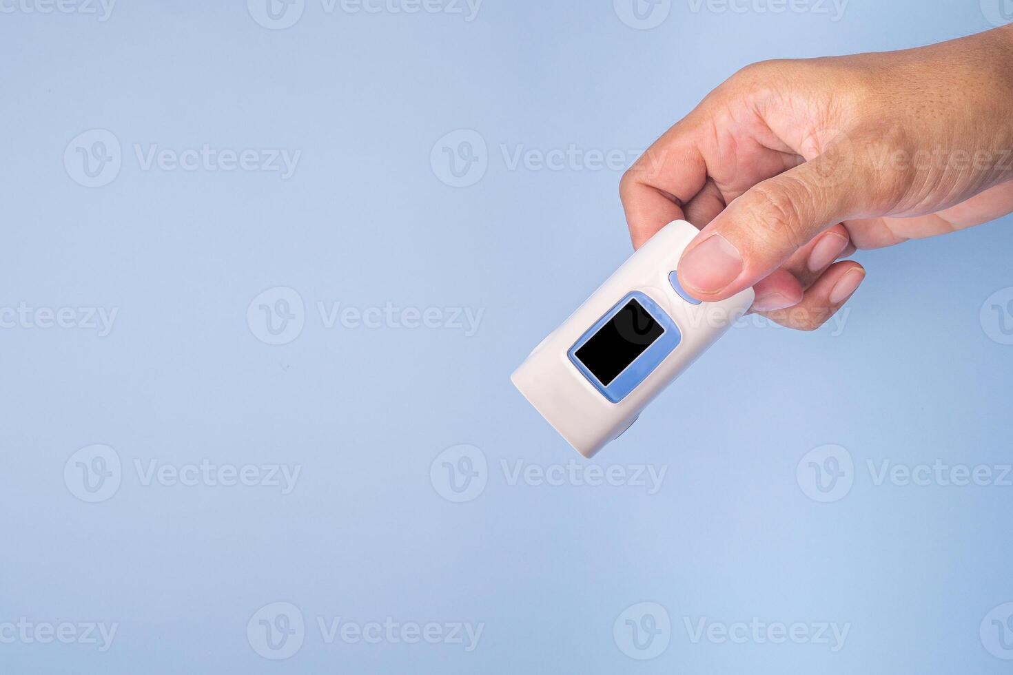 Hand holding of a pulse oximeter on a light blue background. Measurement of blood oxygen and pulse. Lung disease. Close-up photo. Space for text. Healthcare concept photo