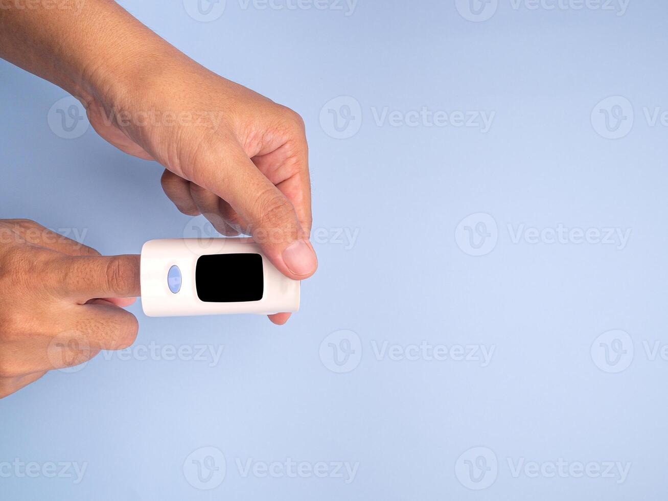 Pulse oximeter on the index finger on a light blue background. Measurement of blood oxygen and pulse. Lung disease. Close-up photo. Space for text. Healthcare concept photo