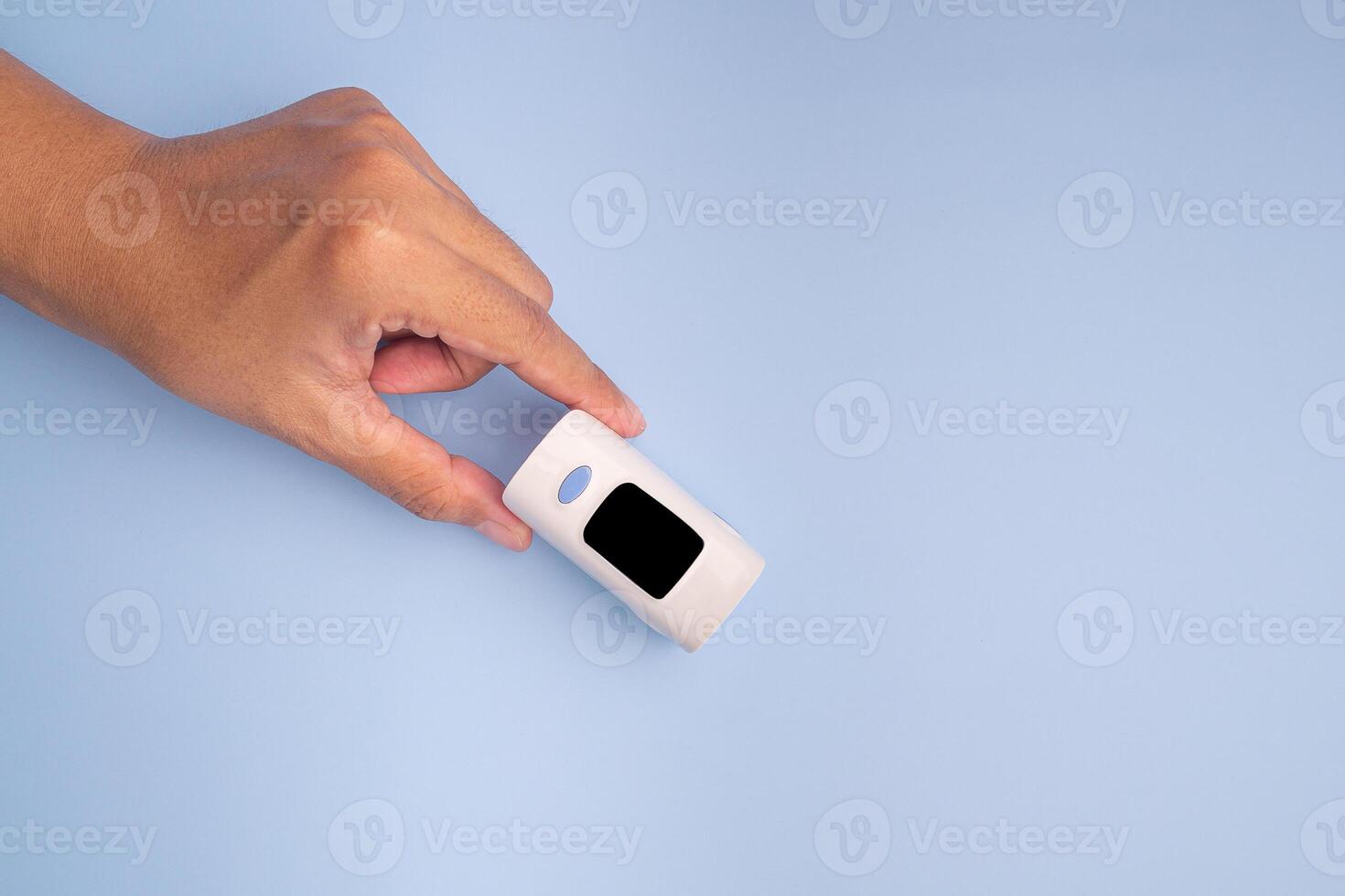 Hand holding of a pulse oximeter on a light blue background. Measurement of blood oxygen and pulse. Lung disease. Close-up photo. Space for text. Healthcare concept photo