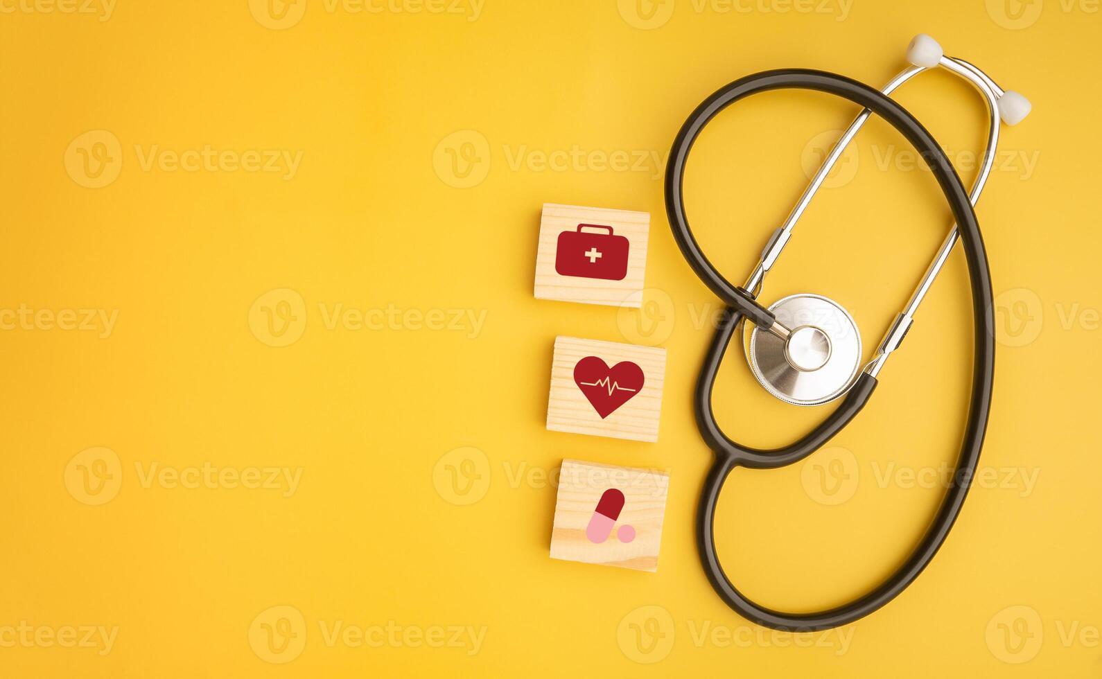 Stethoscope and wooden blocks with icons of health isolated on a yellow background. Close-up photo. Top view. Flat lay with Space for text. Healthcare and medicine with media icons concept photo