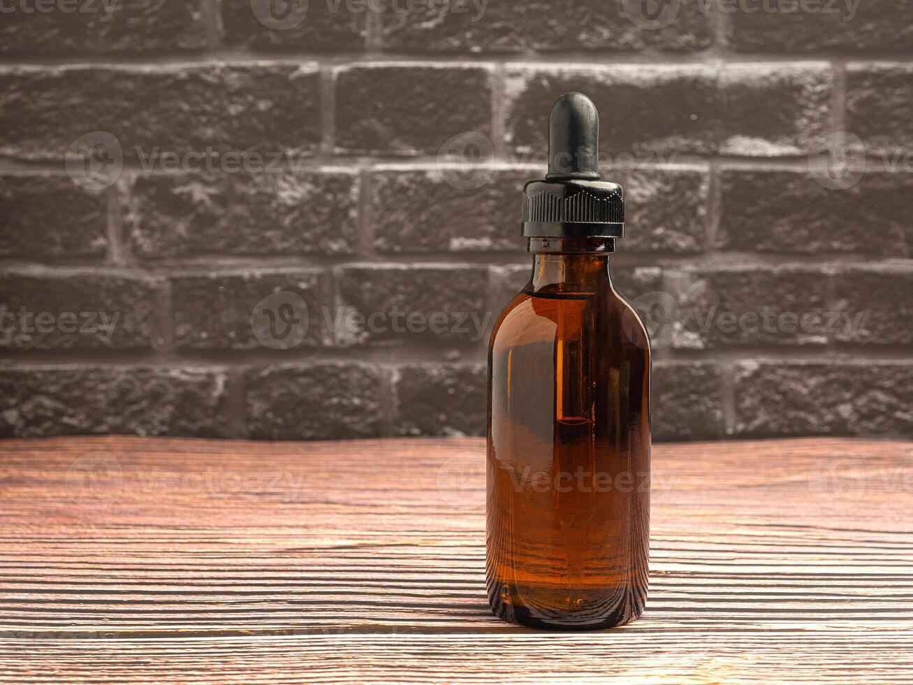 Bottle of cosmetics, natural medicine, essential oils, or other liquids on wooden background with a gray brick wall, Close-up photo. Space for text photo