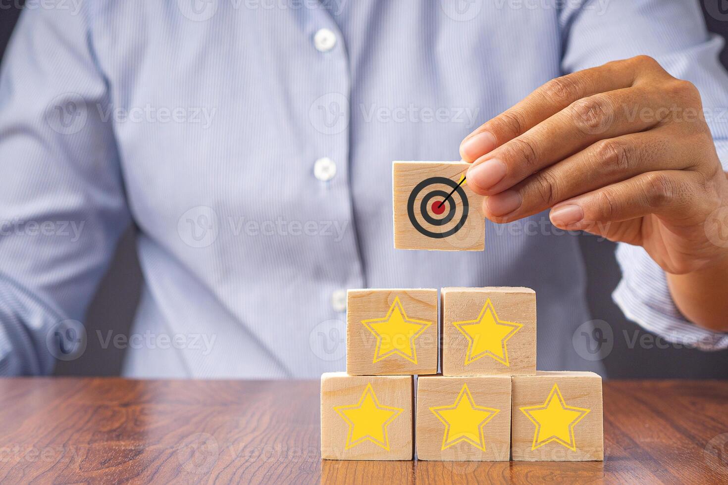 Close-up of hand holding a wooden block with the five-star and target symbol. Concept of business, feedback, and service serving concept photo