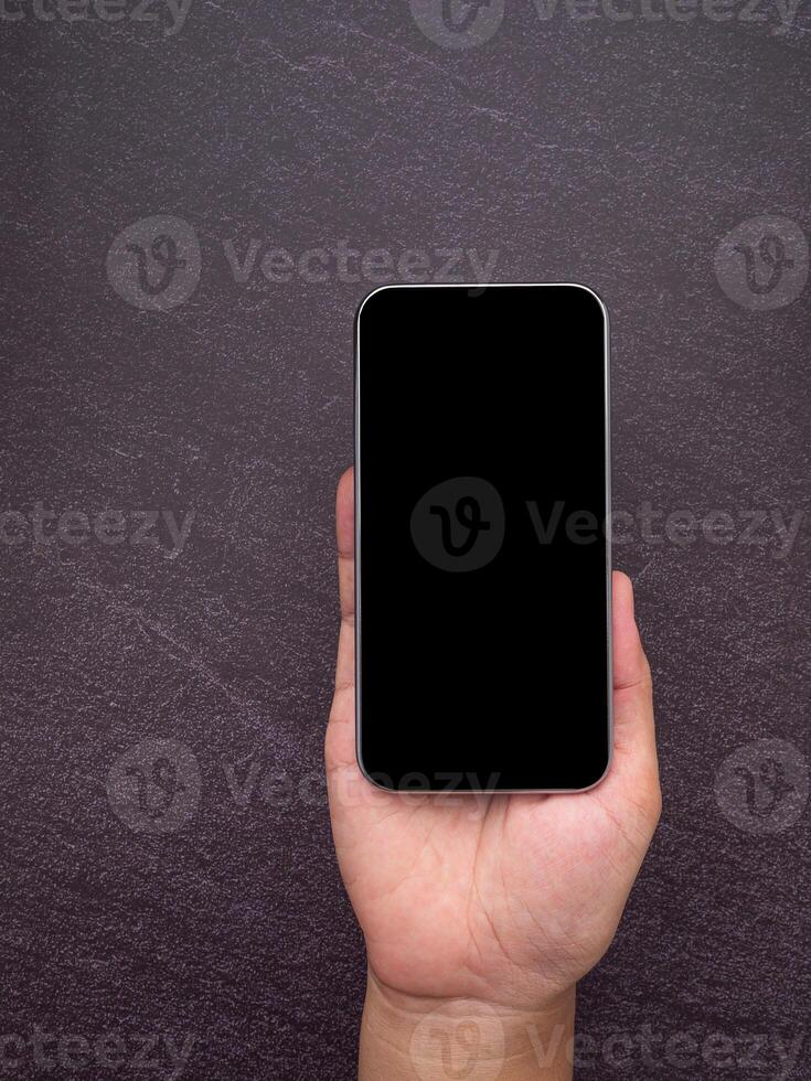 Close-up of a smartphone with blank screen on the palm hand with a gray stone background. Technology and communication concept photo