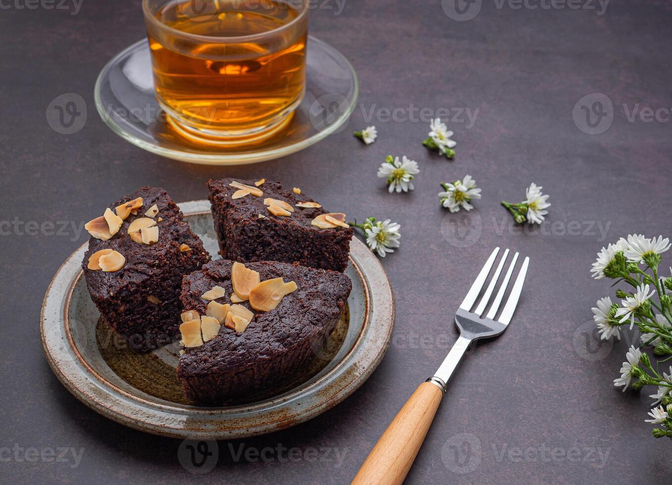 Pieces of fresh brownies on a plate with a teacup. Side view. Delicious chocolate pie. Dessert and relaxation concept photo
