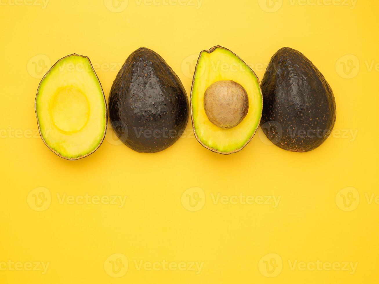 Top view of the fresh avocado whole and half placed on a yellow background. Organic fruit. Space for text. Concept of healthy fruits and healthcare photo