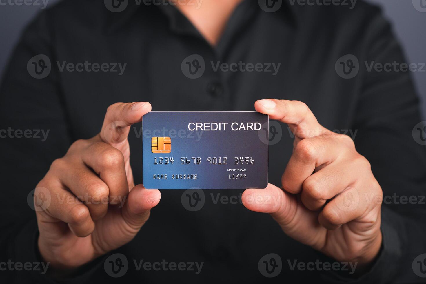 Businessman holding a mockup blue credit card while standing in a studio with copy space for text. Close-up photo. Money and business concept photo