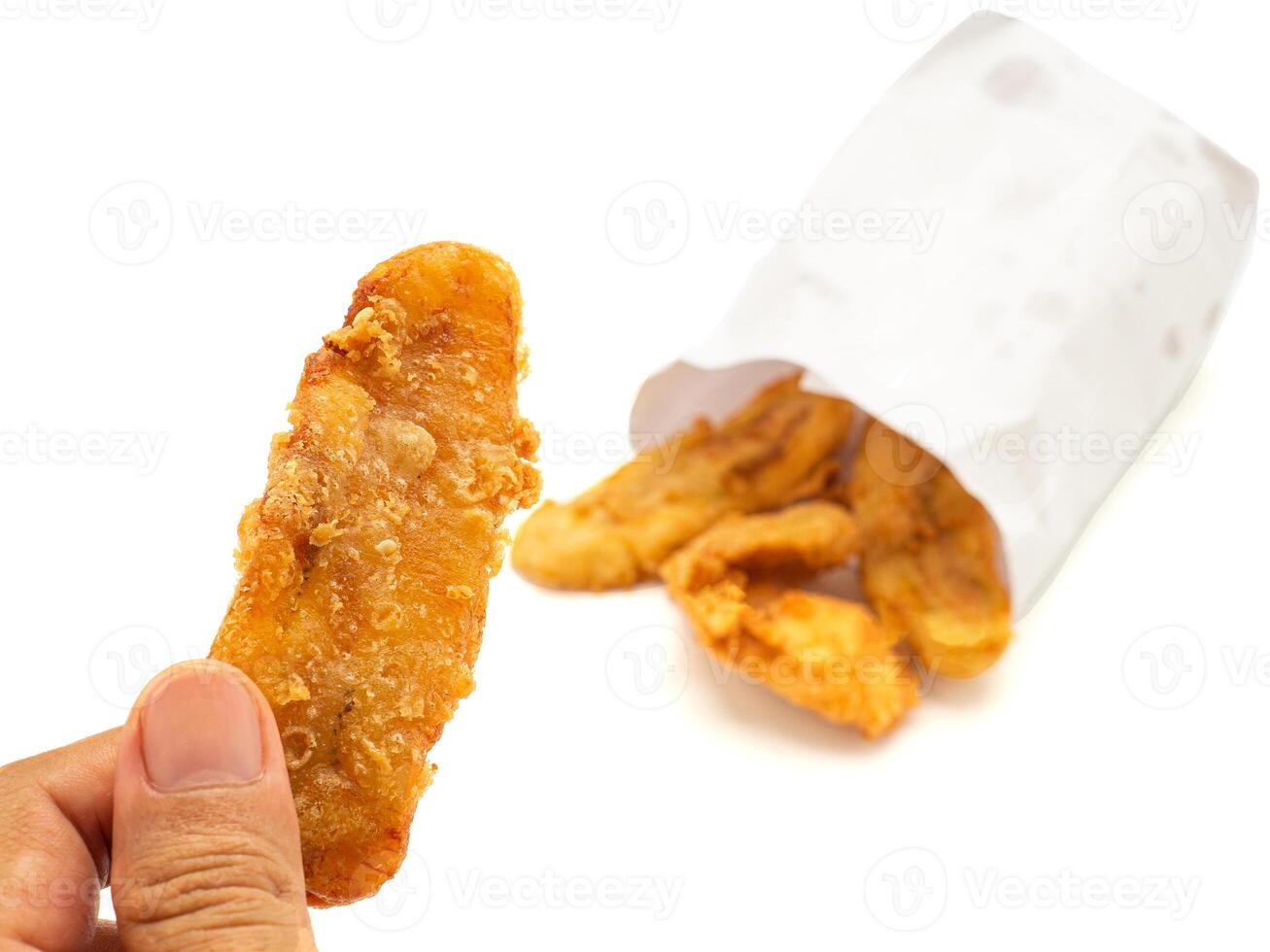Hand holding a fried banana with a paper bag placed on white background photo