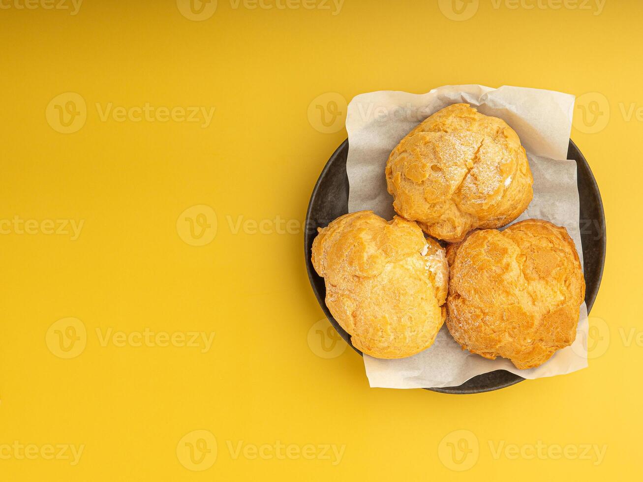 Top view of choux cream on a plate placed on a yellow background. Space for text. Concept of dessert and relaxation photo