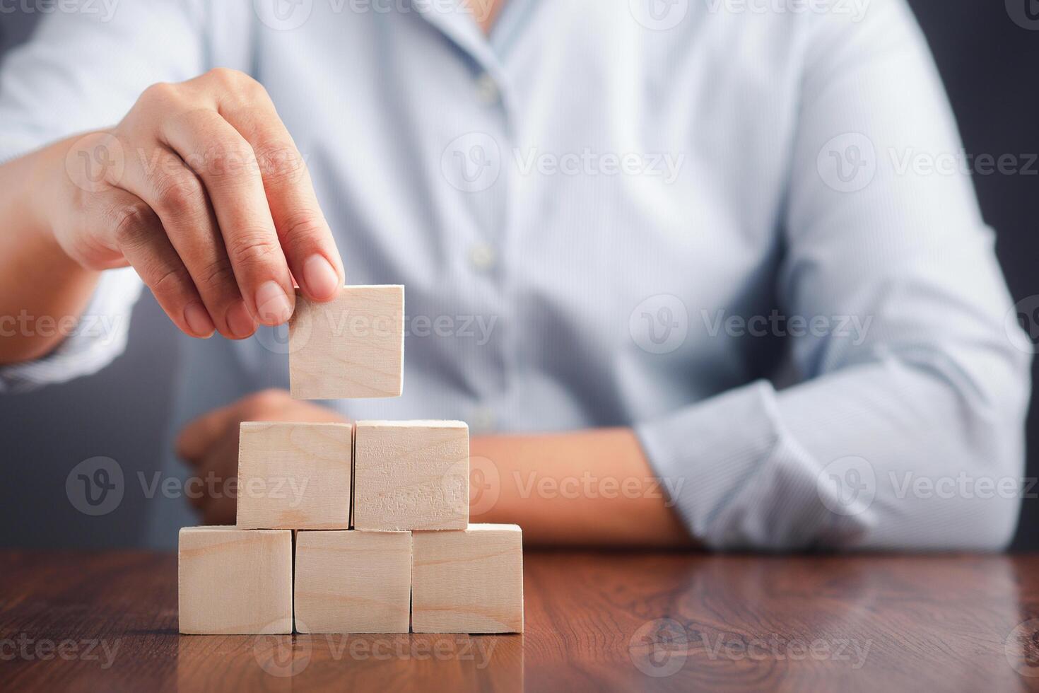 Hand holding a blank wooden block while sitting on a chair. Close-up photo. Space for text photo