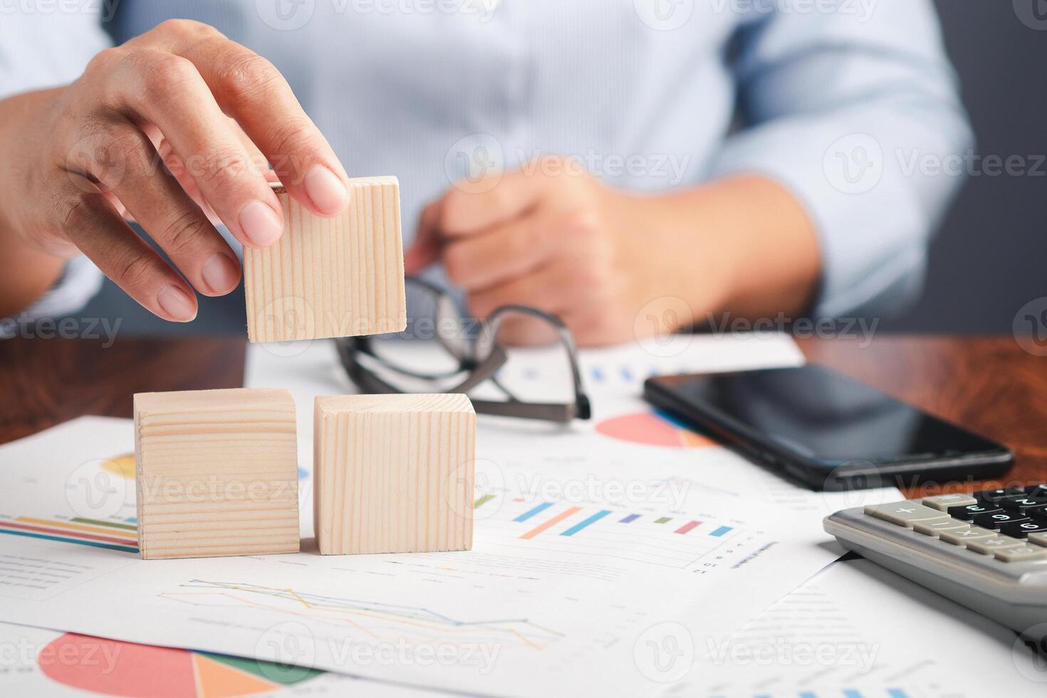 Hand holding a blank wooden block while sitting on a chair. Close-up photo. Space for text photo
