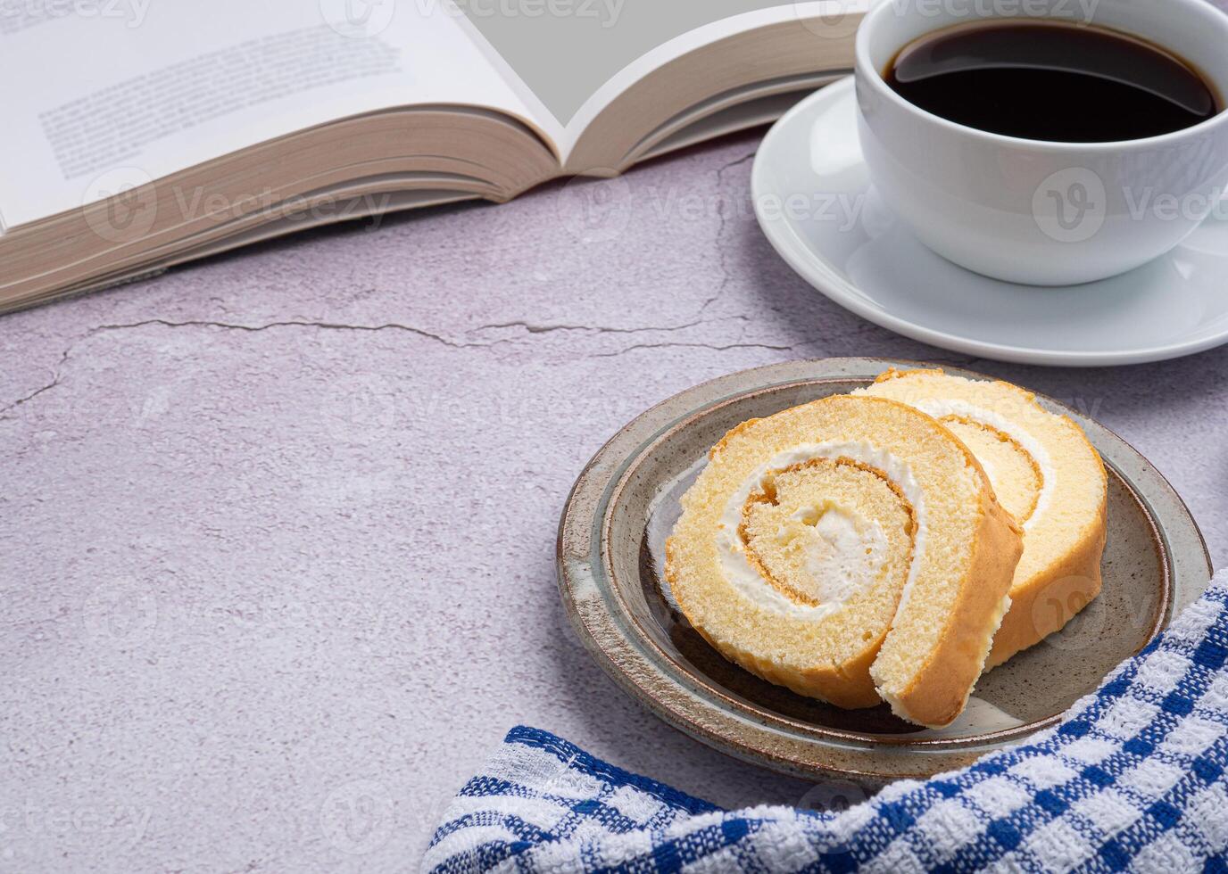 Top view of a book with roll cakes on a plate, a white coffee cup, and a cloth placed on a gray stone background. Space for text. Concept of relaxation photo