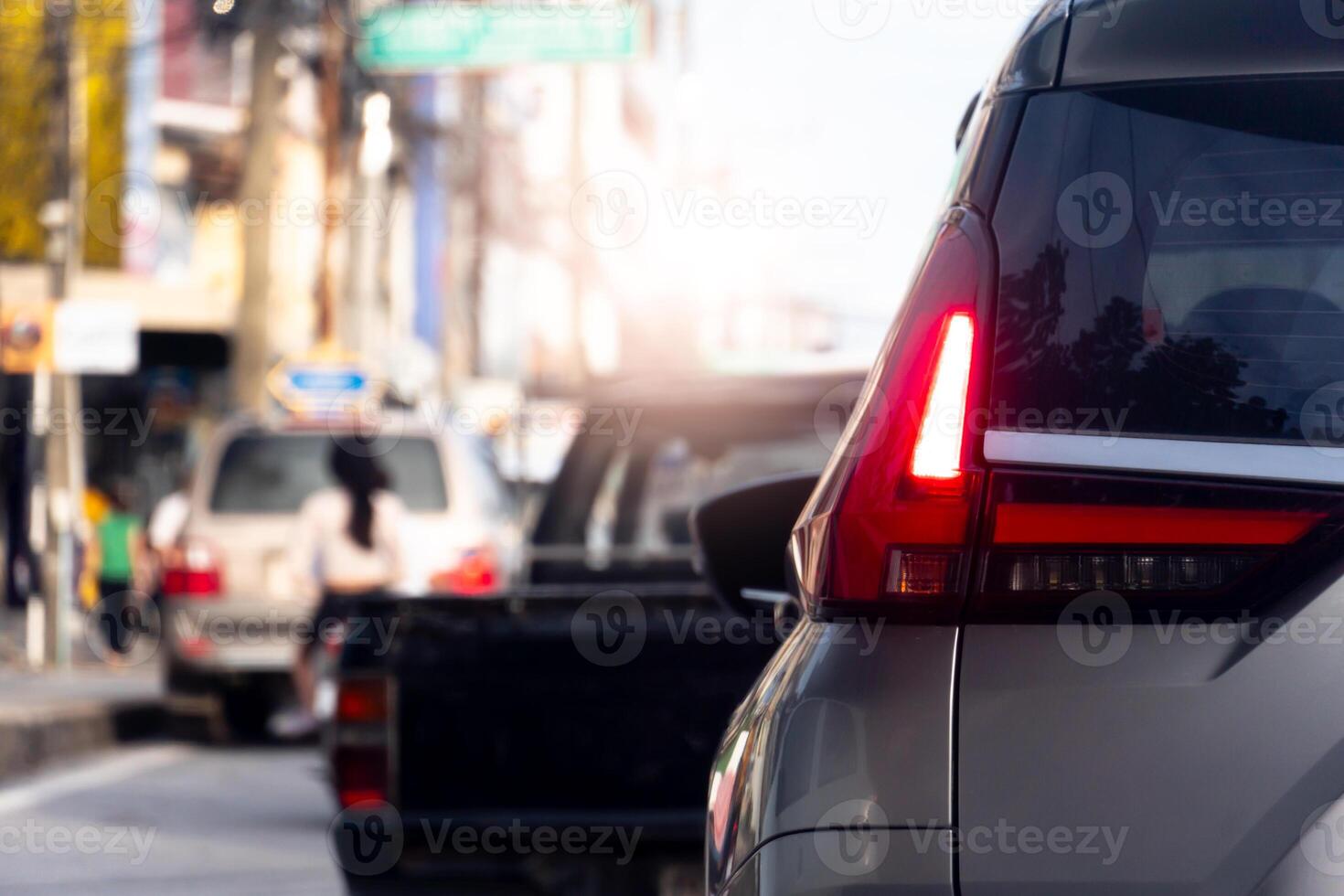 Luxury of grey car stop on the asphalt road. Traveling in the provinces during the bright period. Open light brake. Many cars rushed forward in a long queue. Beside of residential building. photo