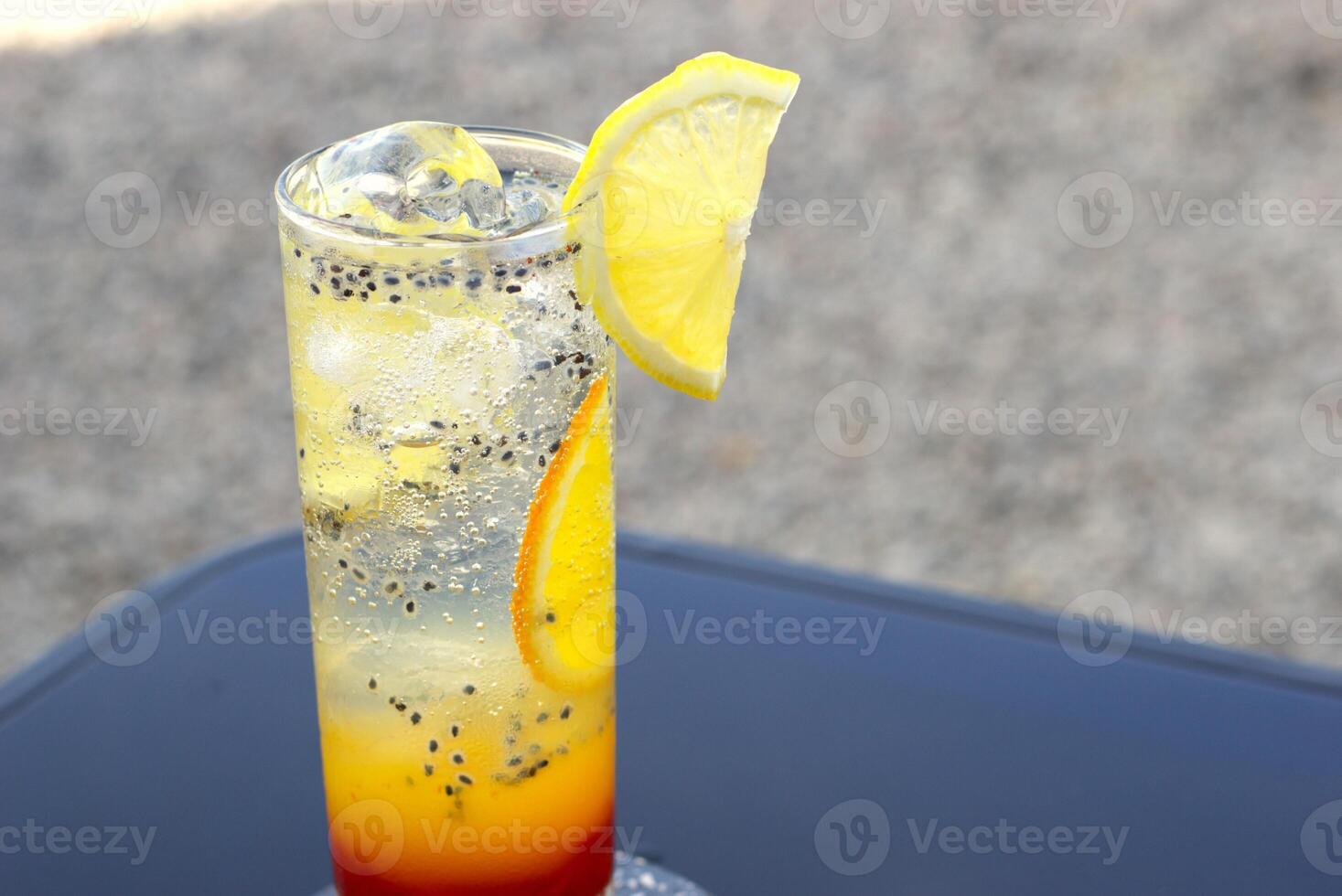 cold summer drink with slice of lemon and basil seed in an outdoor cafe photo