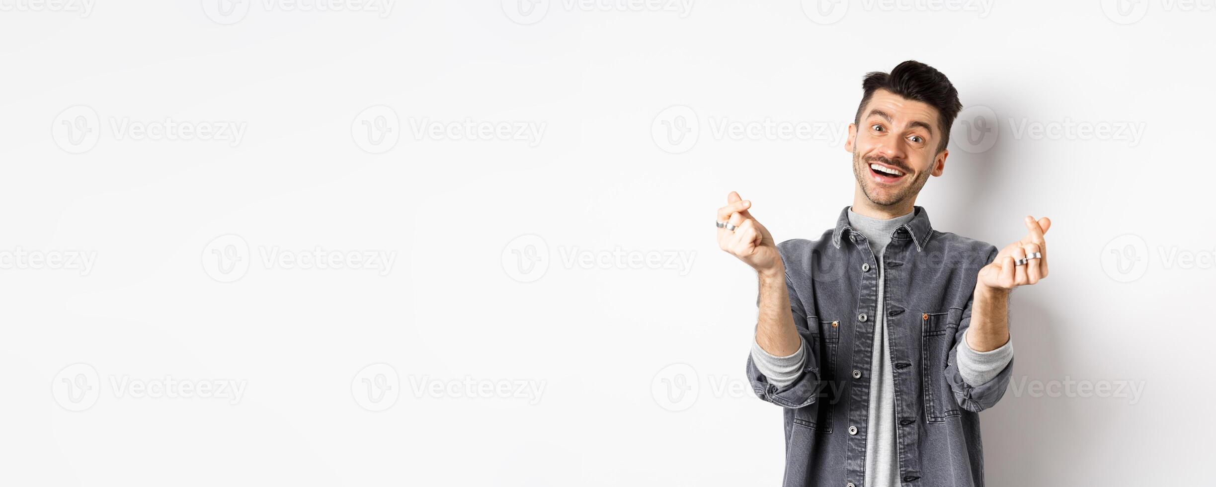 Handsome smiling man showing hand hearts and looking with love at camera, standing on white background photo