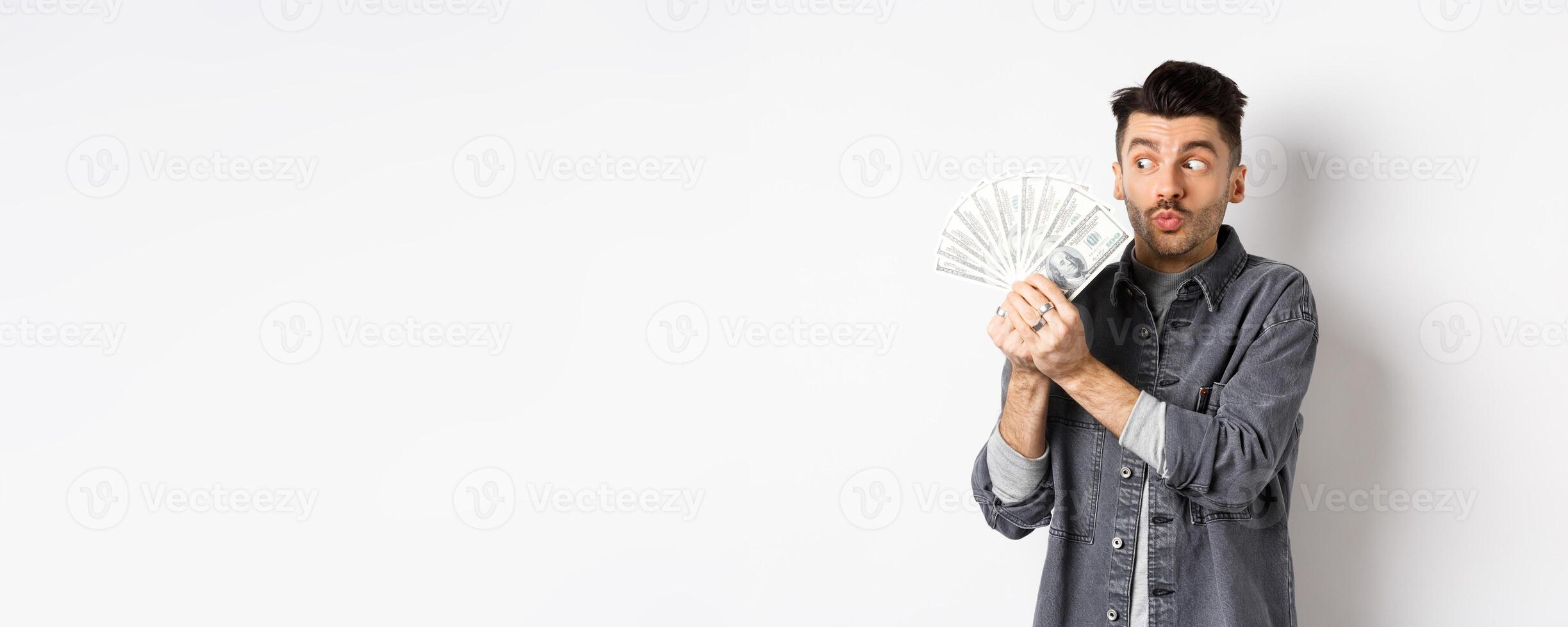 Excited man hugging and kissing dollar bills, holding money and rejoicing, standing on white background photo