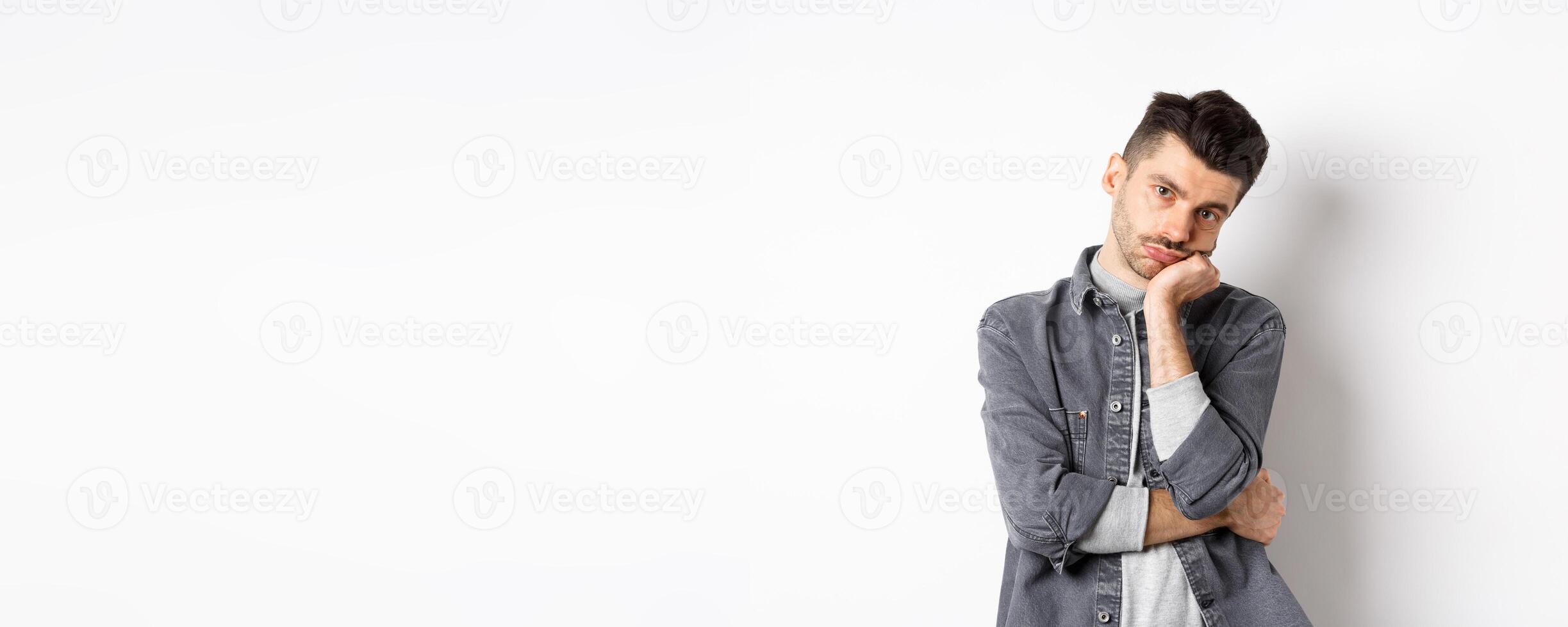 Bored and reluctant stylish guy look at camera without emotions, attend boring meeting, standing on white background photo