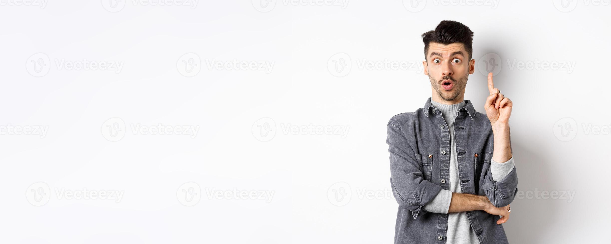 Excited bearded guy pitching an idea, raising finger up in eureka gesture and say suggestion, have a plan, standing on white background photo
