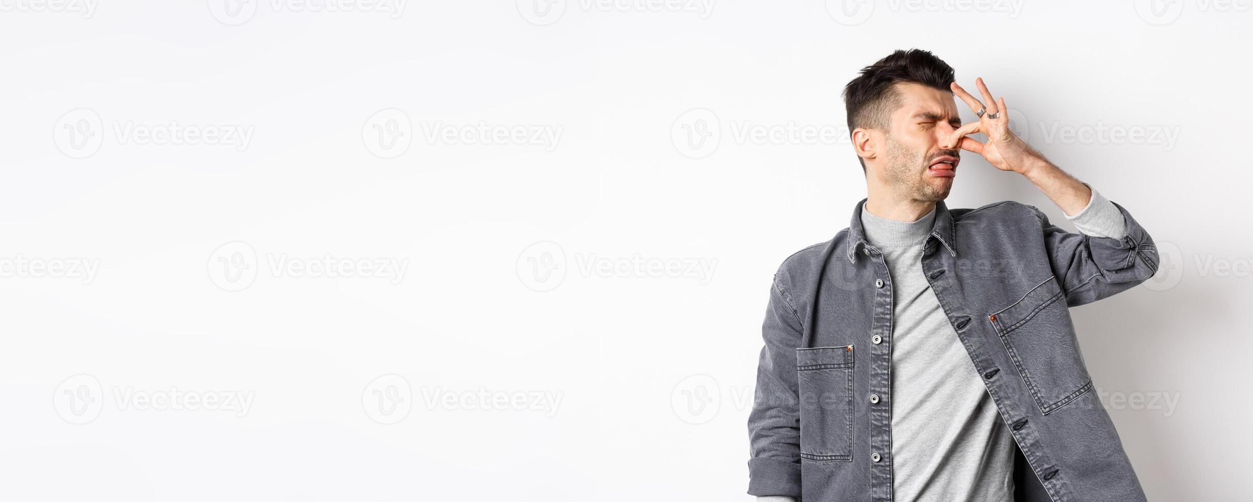 Disgusted man turn away and shut nose from bad smell, disgusting reek, standing on white background photo