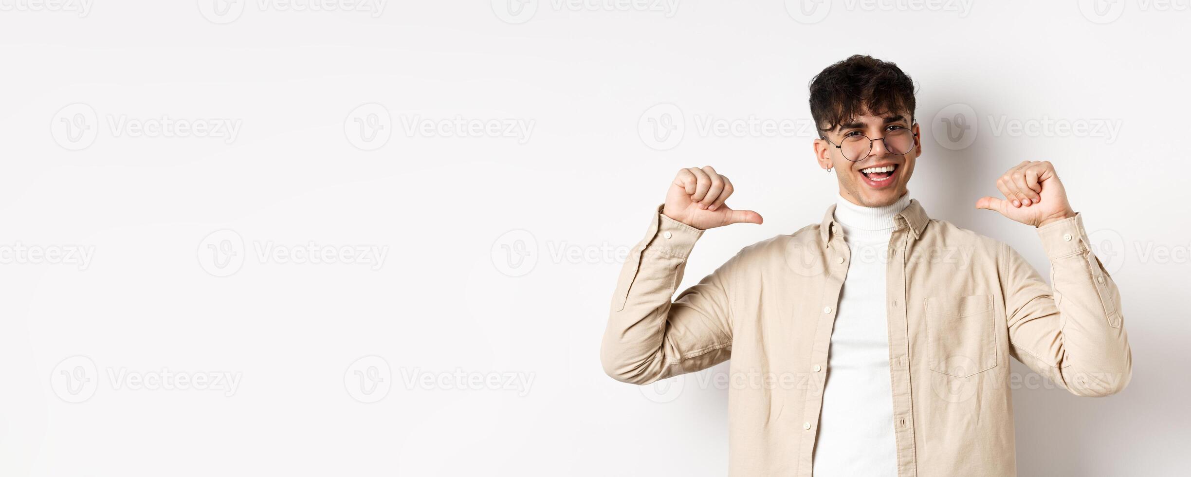 Image of motivated smiling handsome man pointing at himself, self-promoting and clooking confident, standing on white background photo