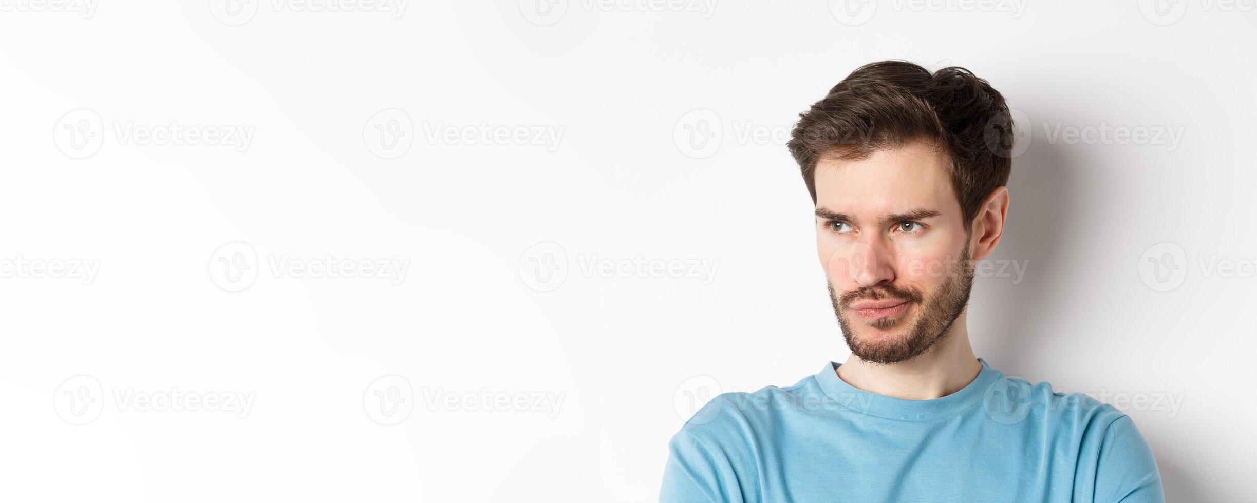 Close-up of disappointed bearded man, sulking and looking left with pensive face, standing upset over white background photo