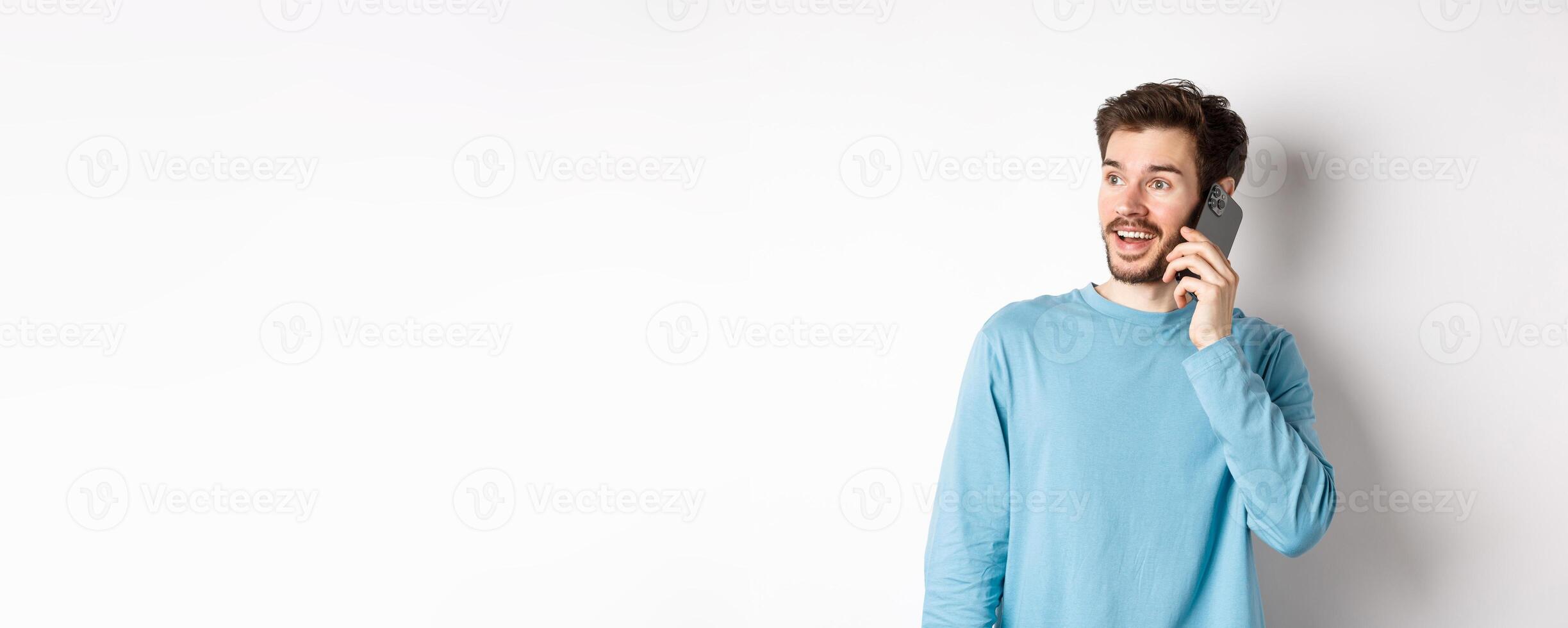 Technology concept. Cheerful man talking on mobile phone, having phone call and looking amused, standing over white background photo