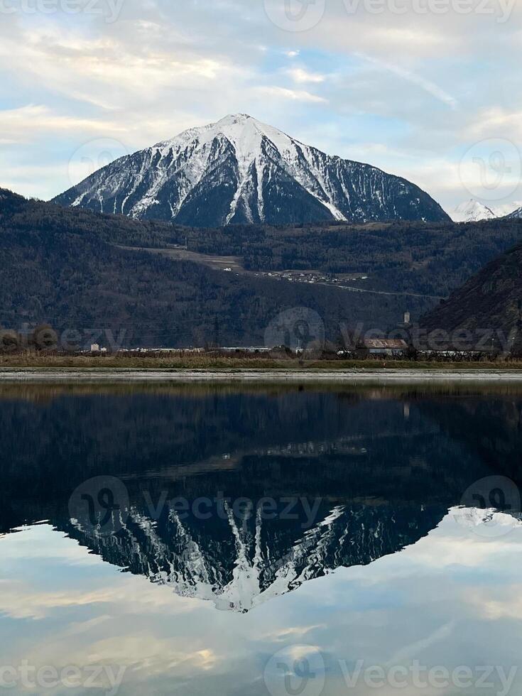 Mirror reflection of a snow-covered mountain in a lake with mountain water in Martigny, Switzerland photo