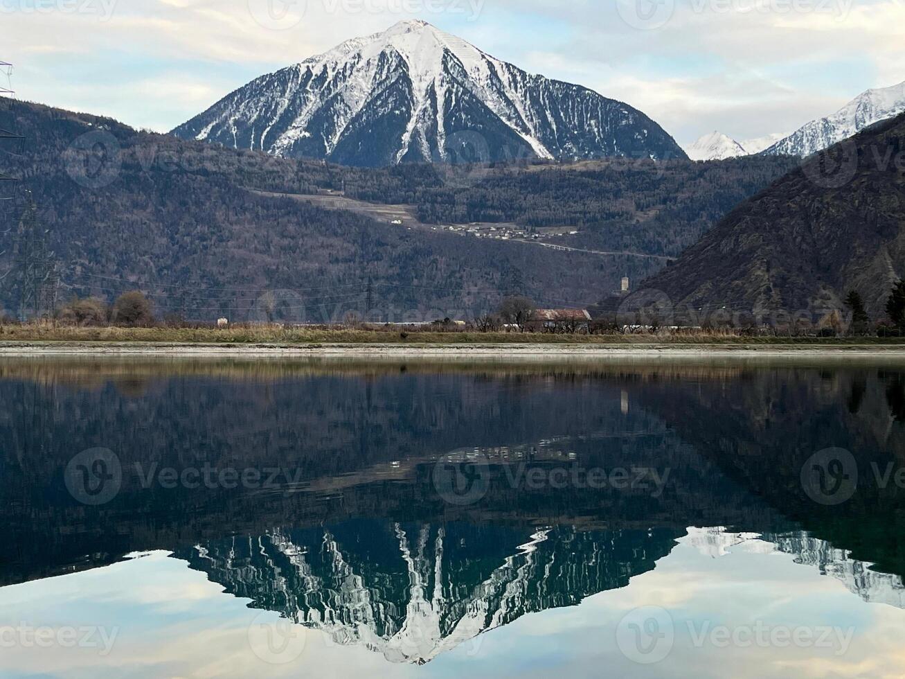 Mirror reflection of a snow-covered mountain in a lake with mountain water in Martigny, Switzerland photo