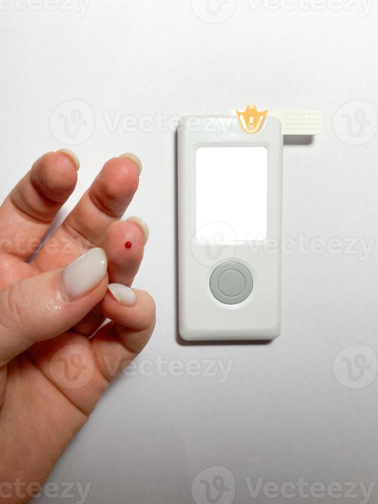 Measurement of blood sugar levels using a glucose meter with a mock-up. Piercing a finger to draw blood photo