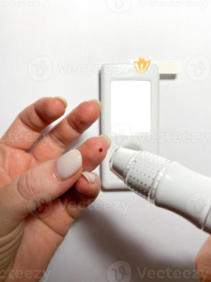 Measurement of blood sugar levels using a glucose meter with a mock-up. Piercing a finger to draw blood photo