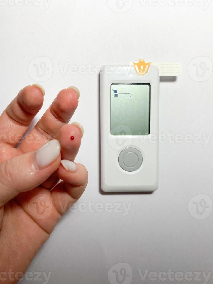 Measurement of blood sugar levels using a glucose meter with a mock-up. Piercing a finger to draw blood photo