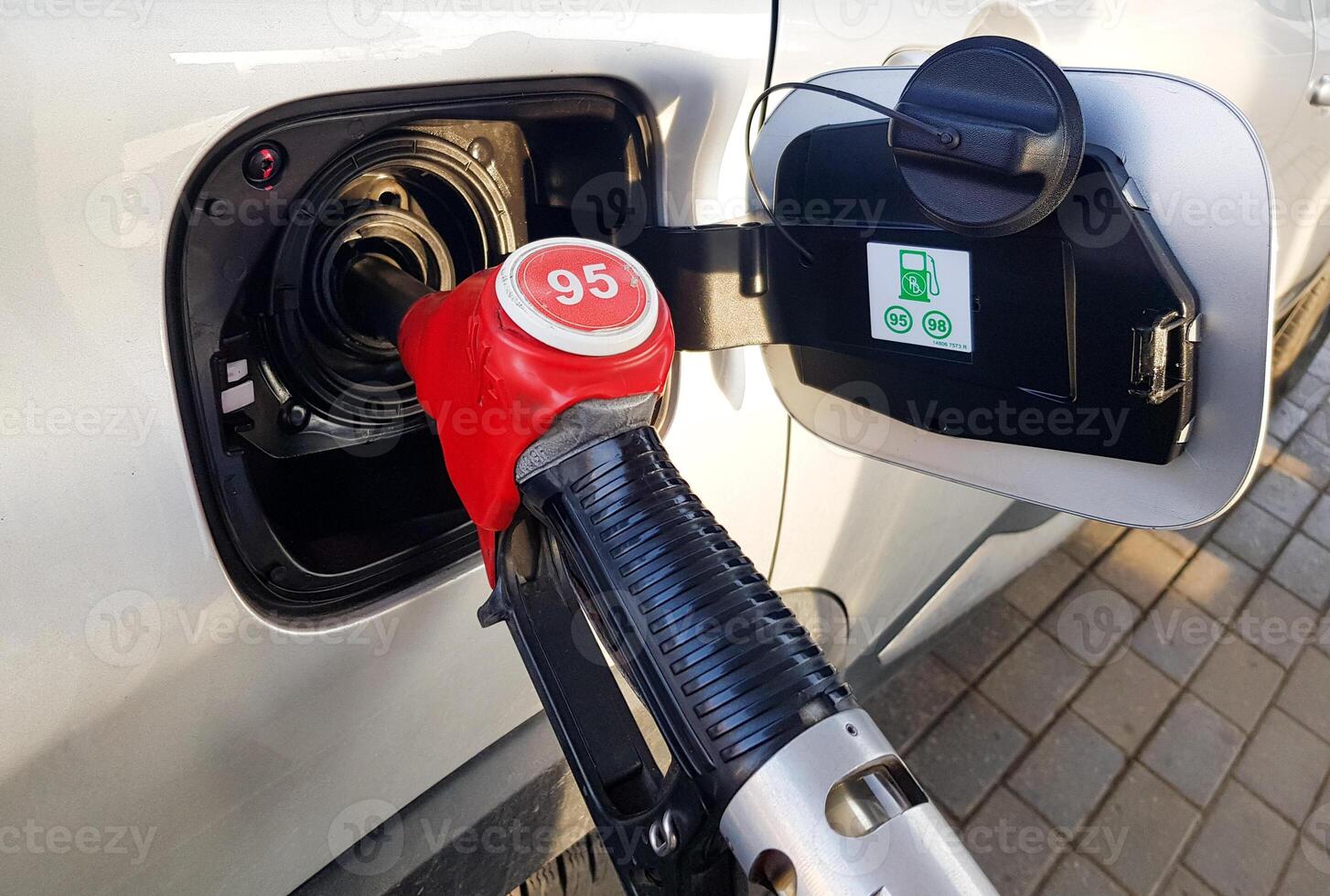 Filling the car with gasoline. Insert the red gun into the tank of the car for refueling. The process of refueling the car with fuel photo