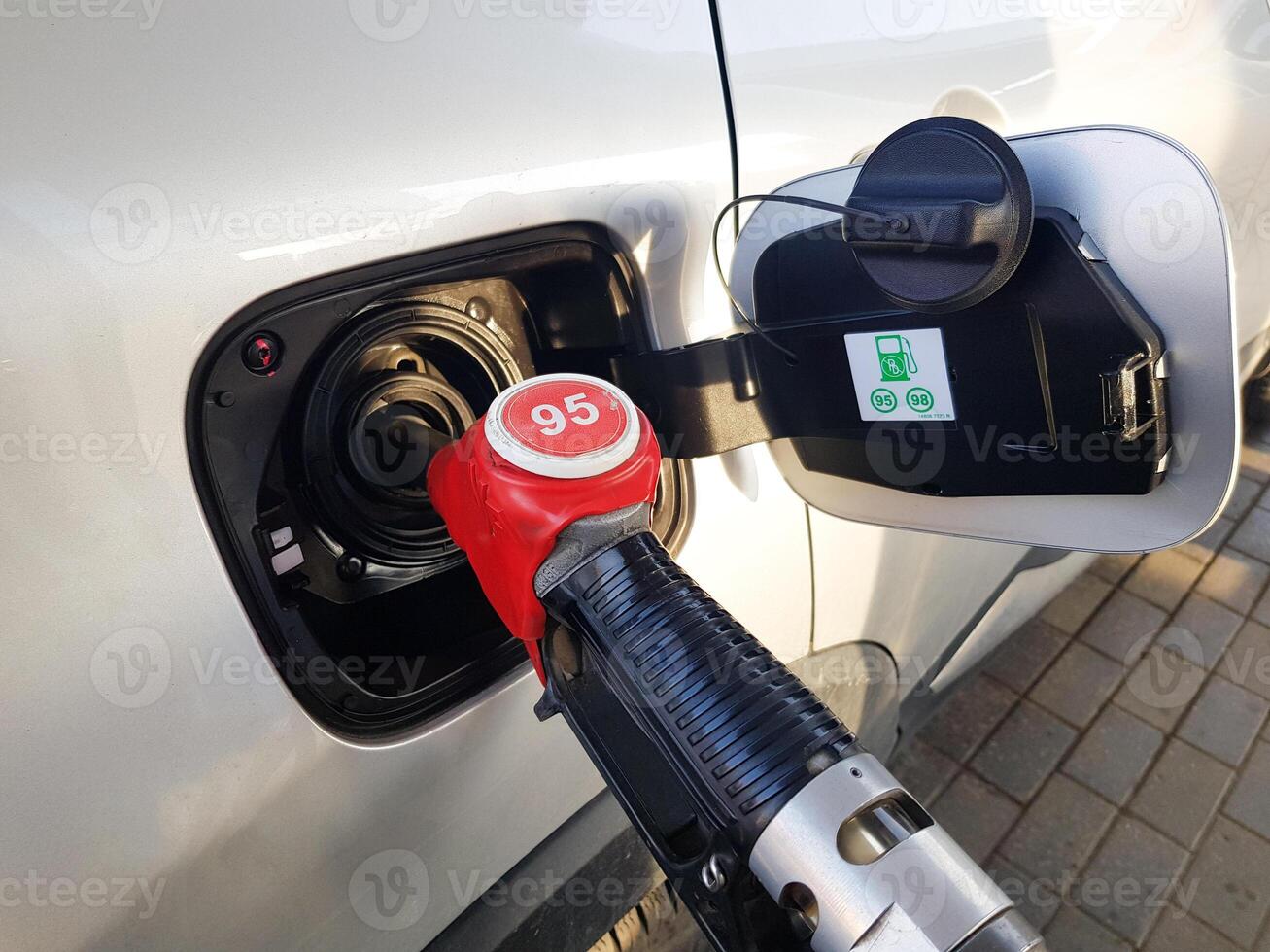 Filling the car with gasoline. Insert the red gun into the tank of the car for refueling. The process of refueling the car with fuel photo