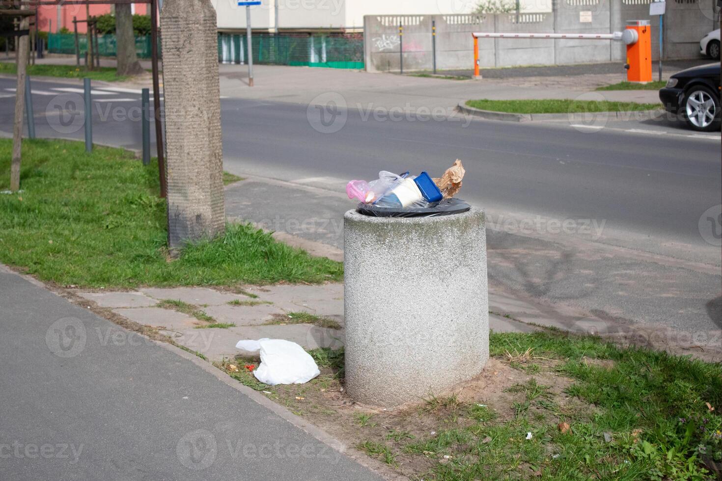 Public trash can on a city street filled with garbage photo