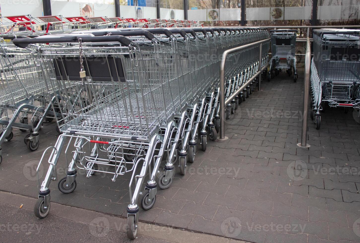Metal grocery carts stand in a store parking bay photo
