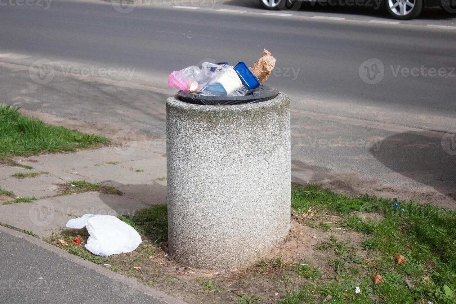 Public trash can on a city street filled with garbage photo