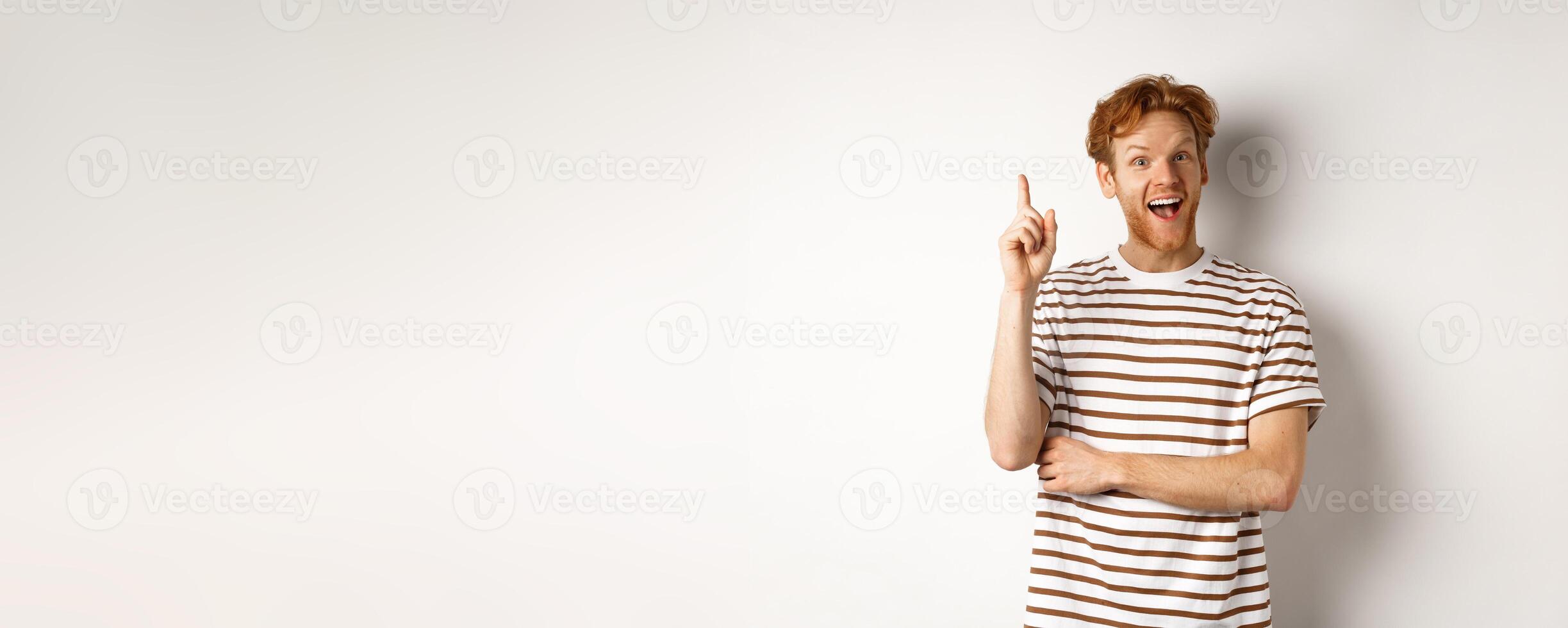 Young man with red hair having an idea, raising finger to say suggestion, standing happy over white background photo