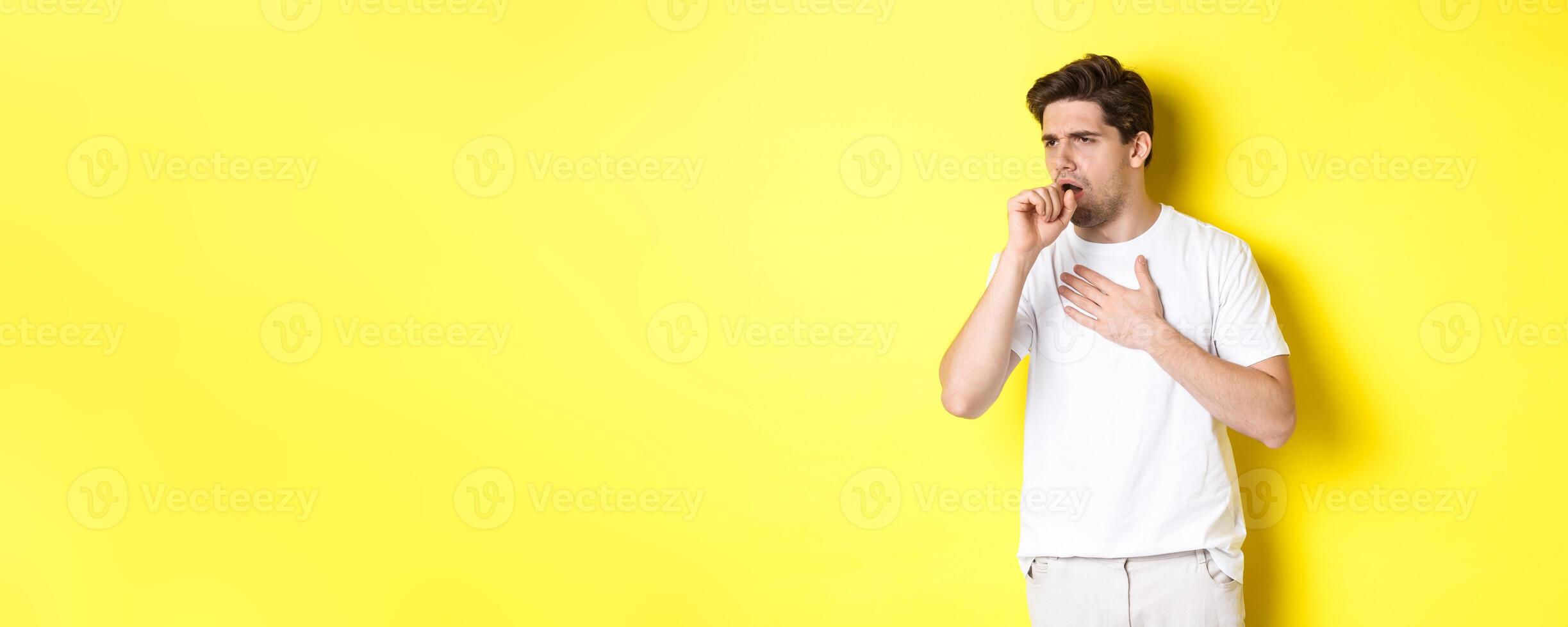 Image of man with covid-19 or flu symptoms, coughing and feeling sick, standing over yellow background photo