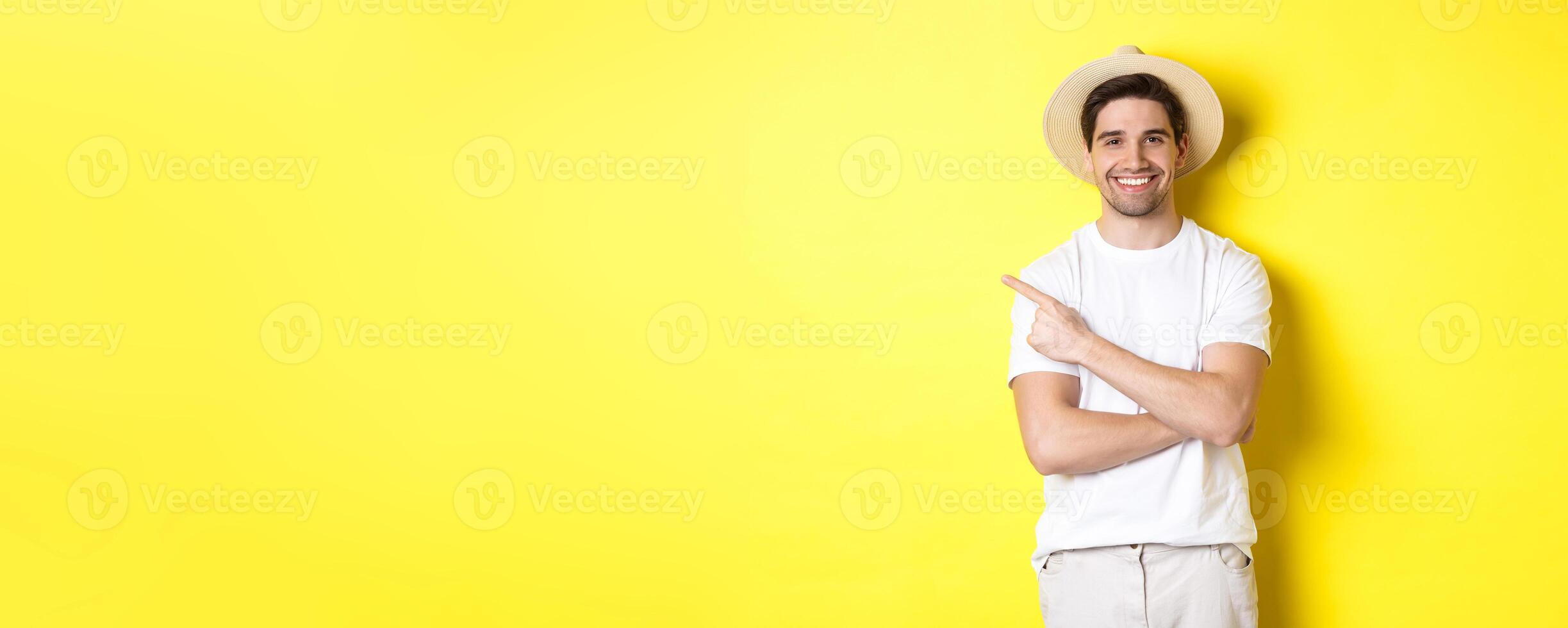 Concept of tourism and lifestyle. Young man tourist pointing finger left, looking happy, showing special holidays promo, yellow background photo
