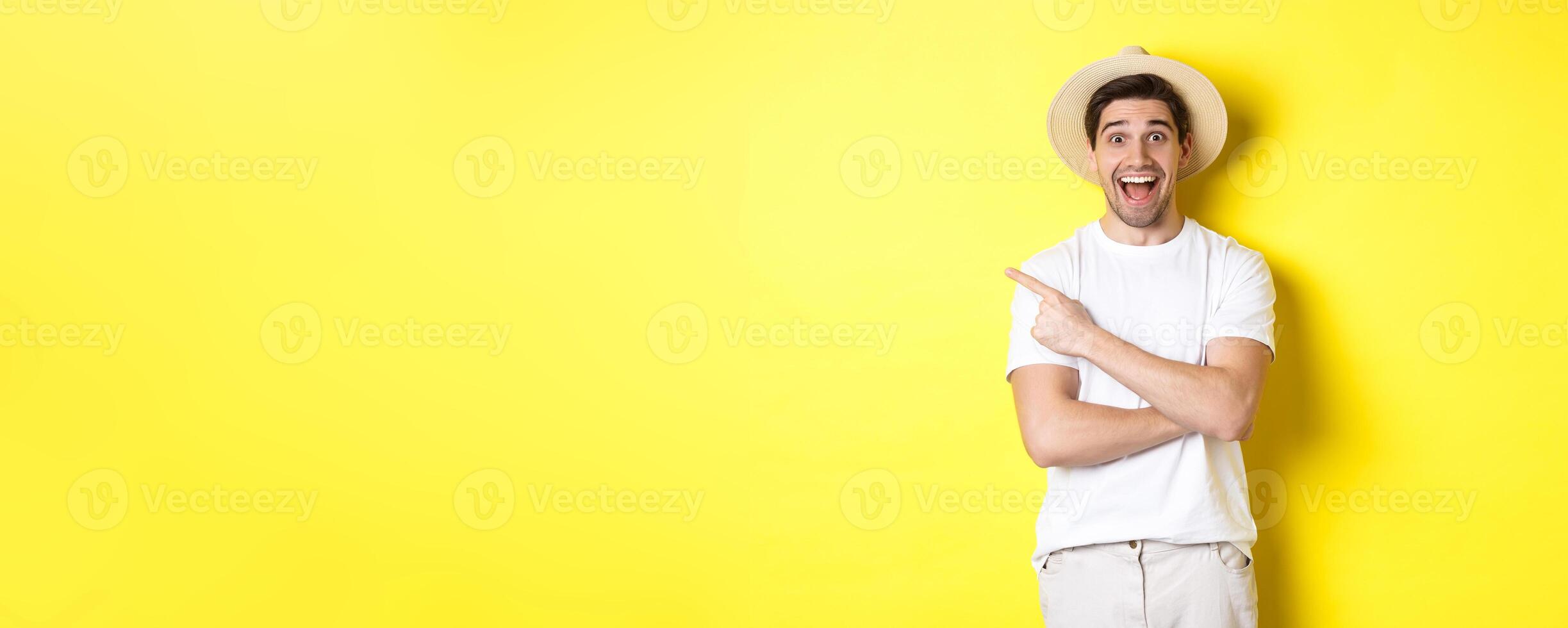 Concept of tourism and lifestyle. Happy young male tourist showing advertisement, pointing finger left and smiling excited, yellow background photo