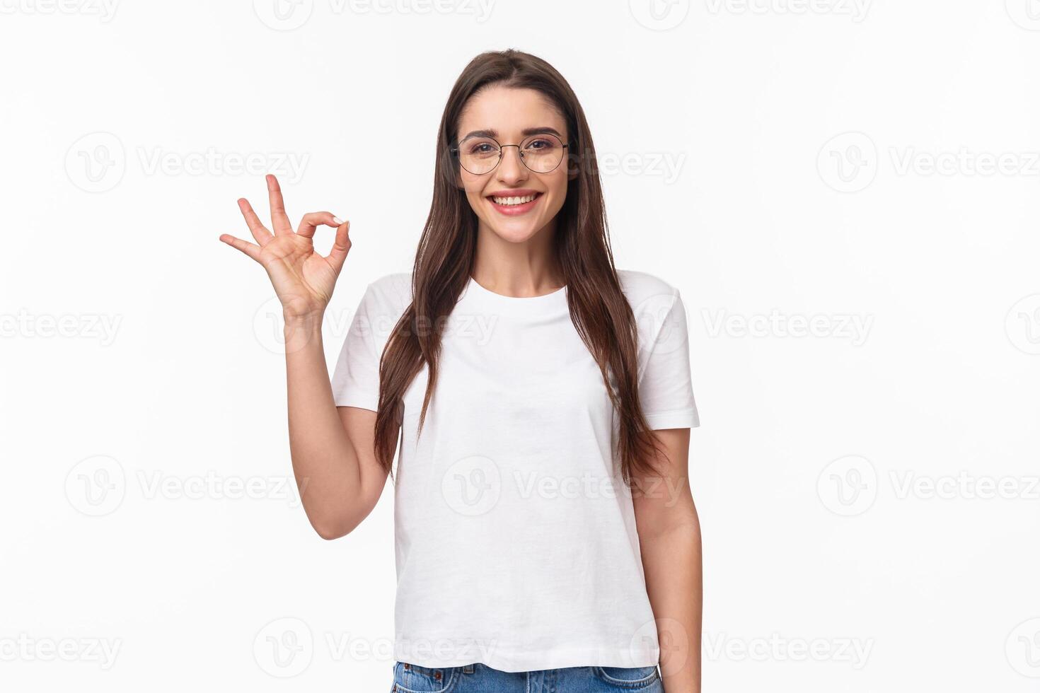 Waist-up portrait of optimistic, smiling happy young pretty woman in glasses, showing okay sign, agree or recommend something, give positive review, approve excellent choice, white background photo