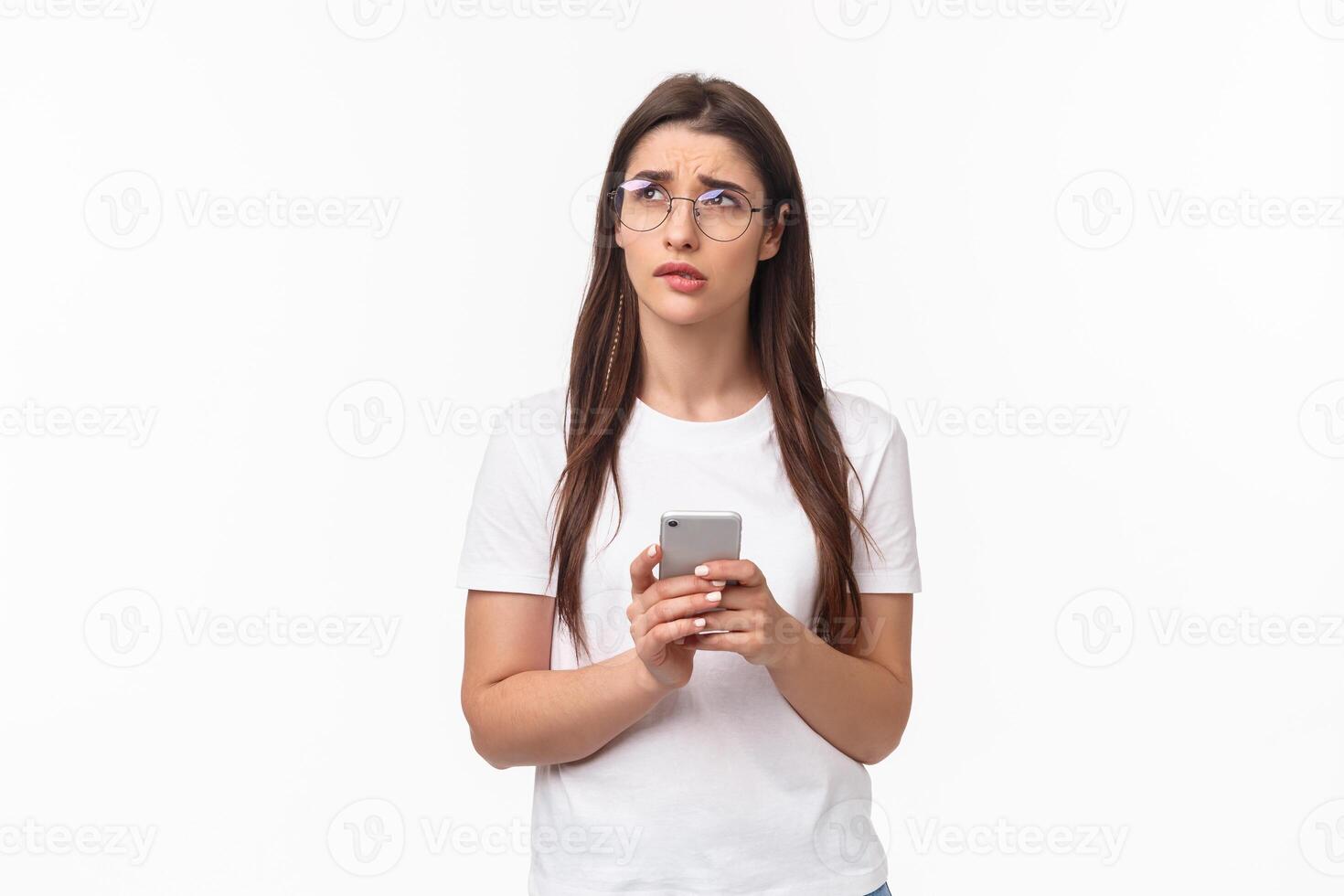 Communication, technology and lifestyle concept. Portrait of troubled and concerned young woman worried for friend, sending text message if shes okay and thinking, look up nervous, hold mobile phone photo